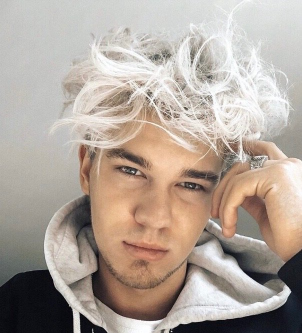 White male with platinum blond bleach and tone hair. Styled in an effortless tousled beach look