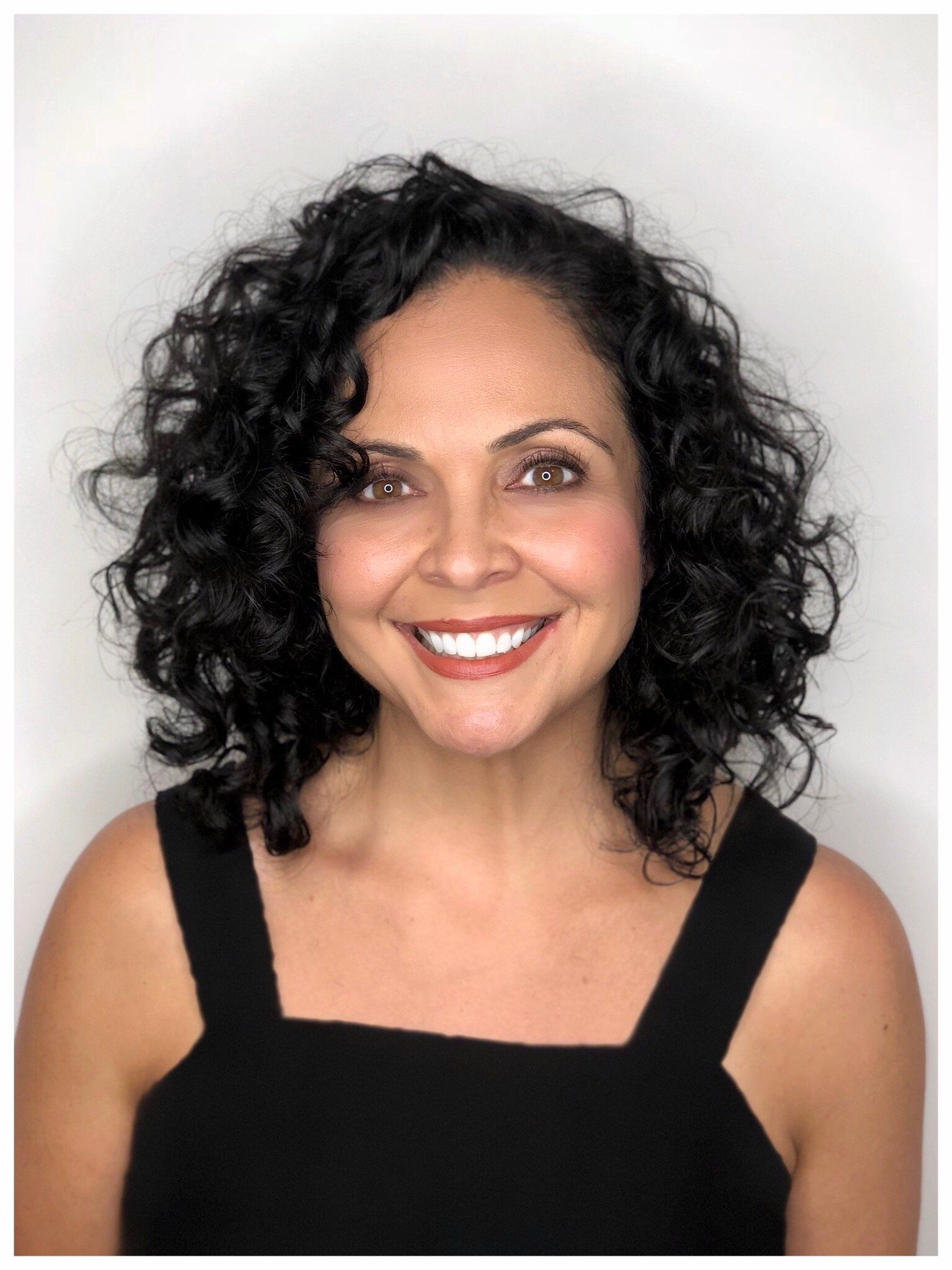 Latina woman smiling with a curly hair bob