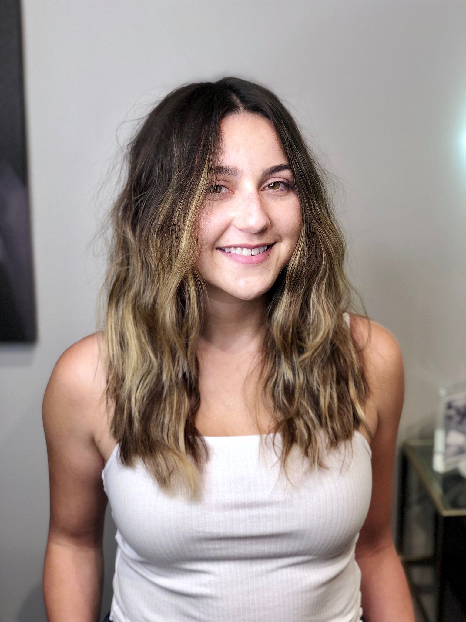 Brunette girl with sun kissed balayage highlights styled with effortless beach waves