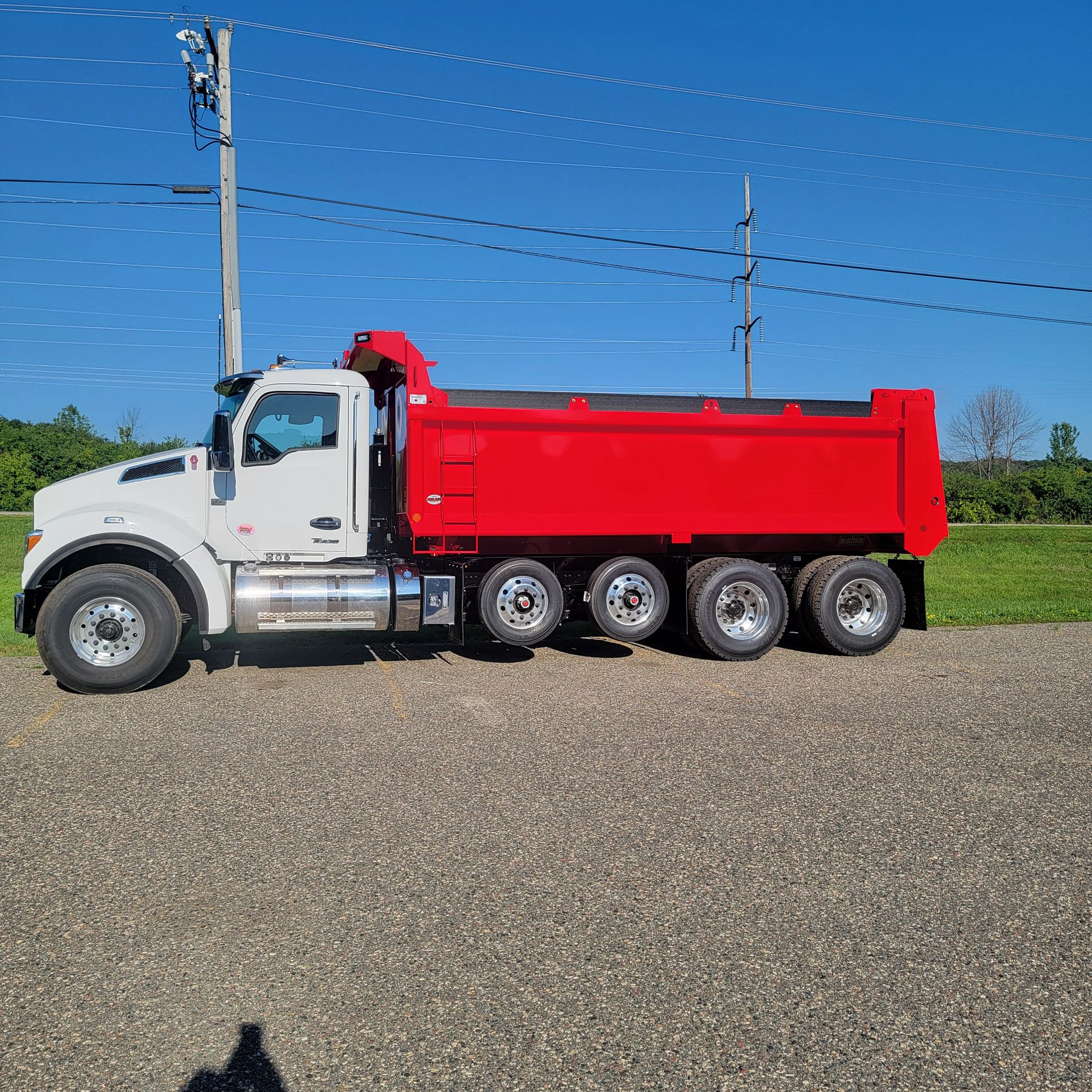 A red dump truck is parked on the side of the road.