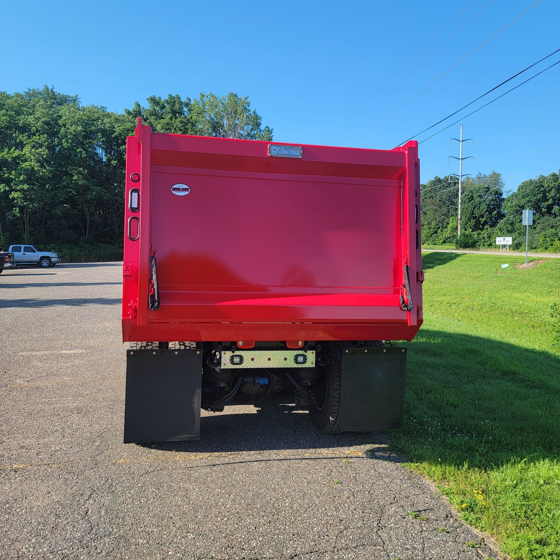 A red dump truck is parked on the side of the road.