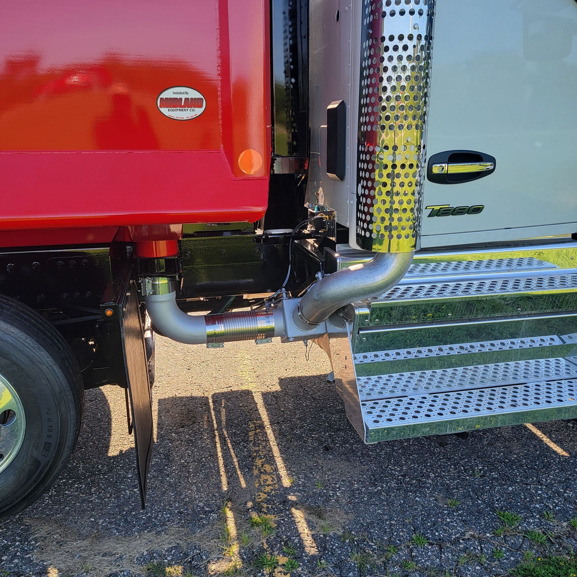 A red dump truck with a stainless steel exhaust pipe