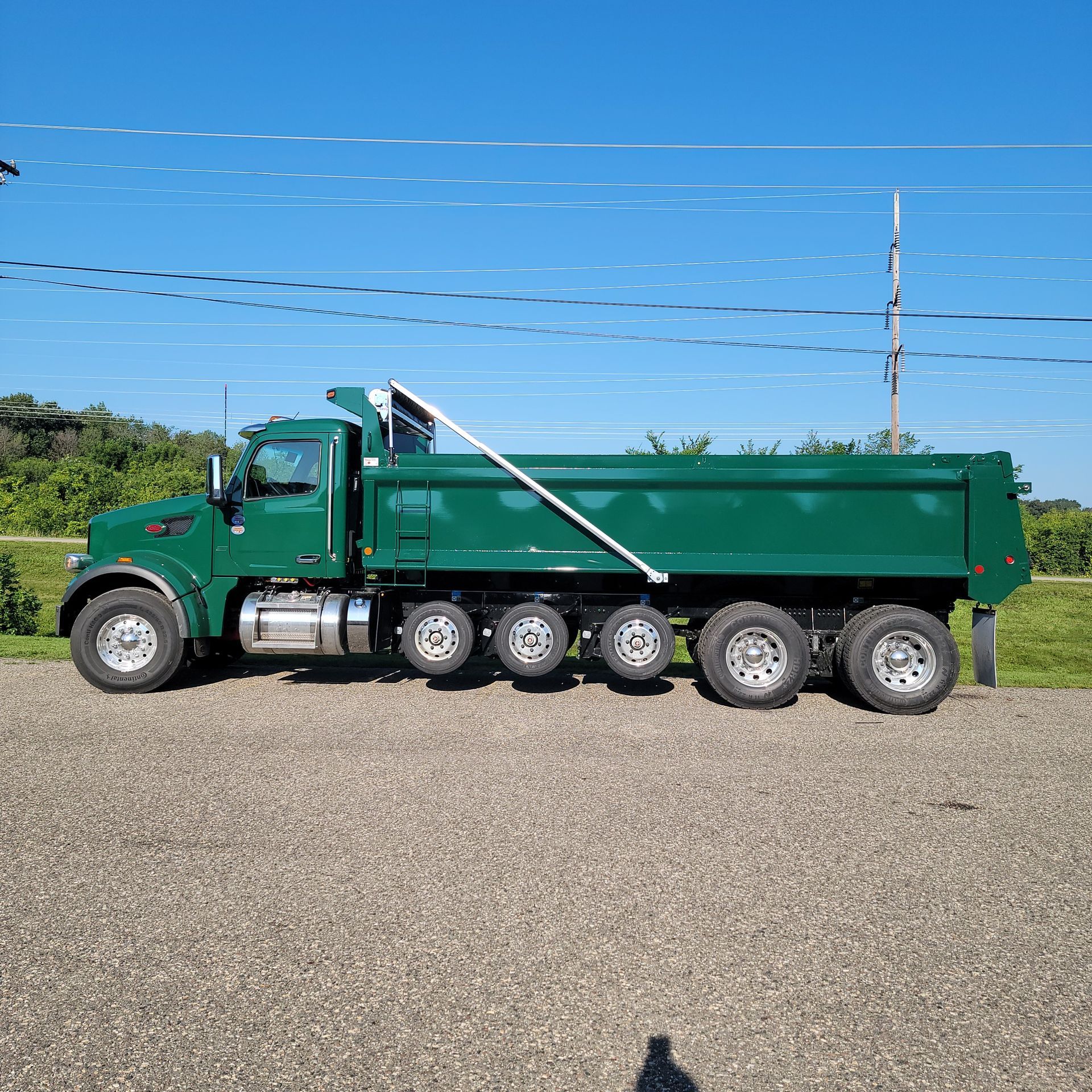 A green dump truck is parked on the side of the road.