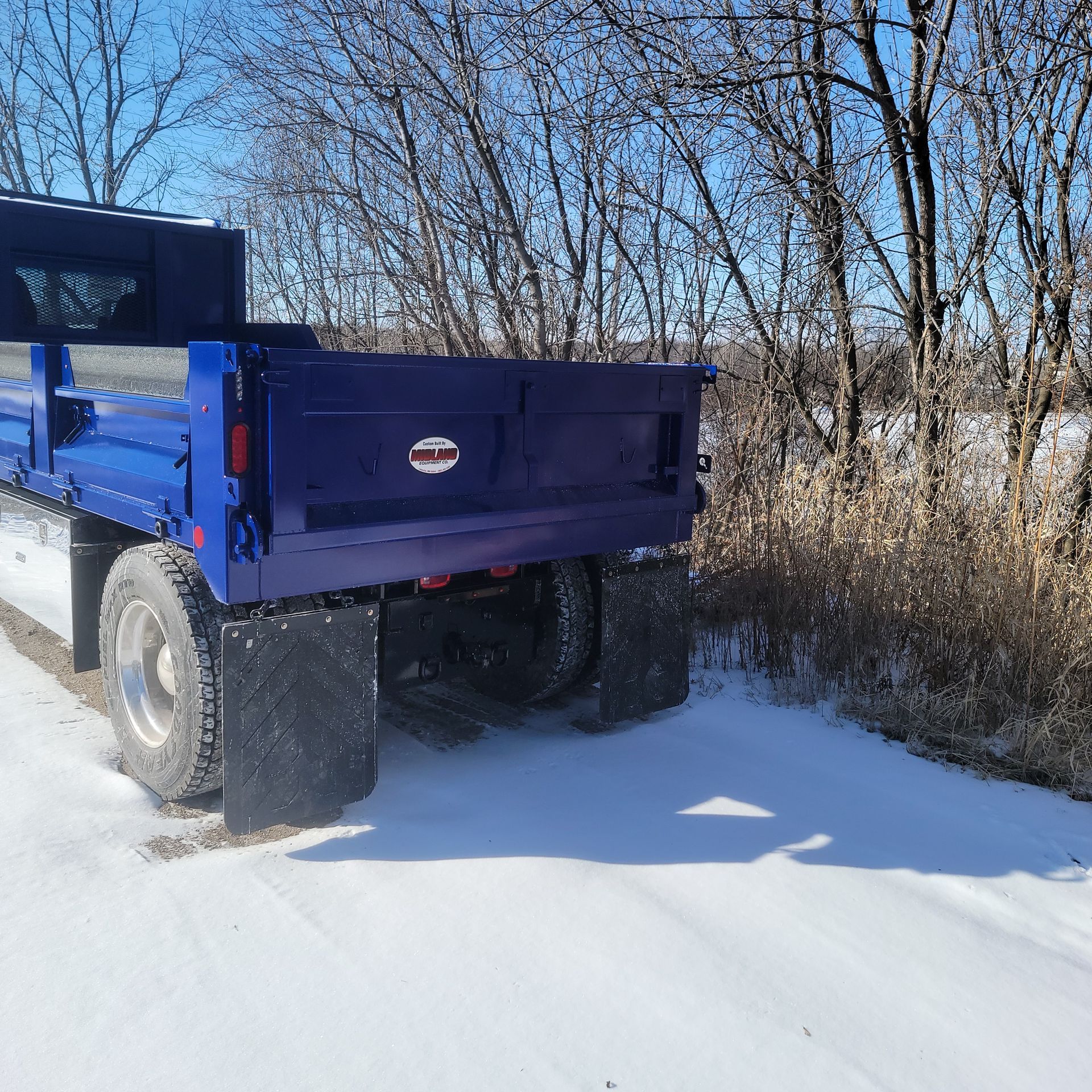 A blue dump truck is parked on a snowy road