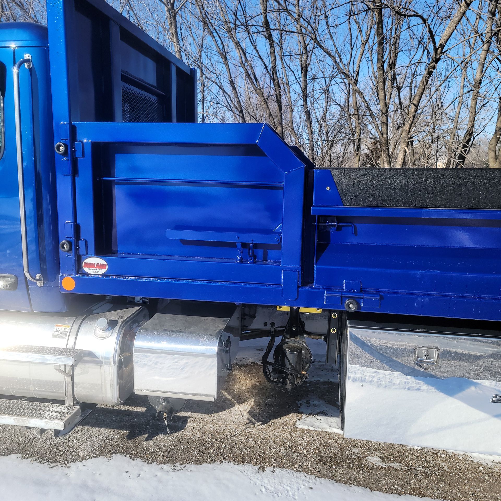 A blue dump truck is parked in the snow