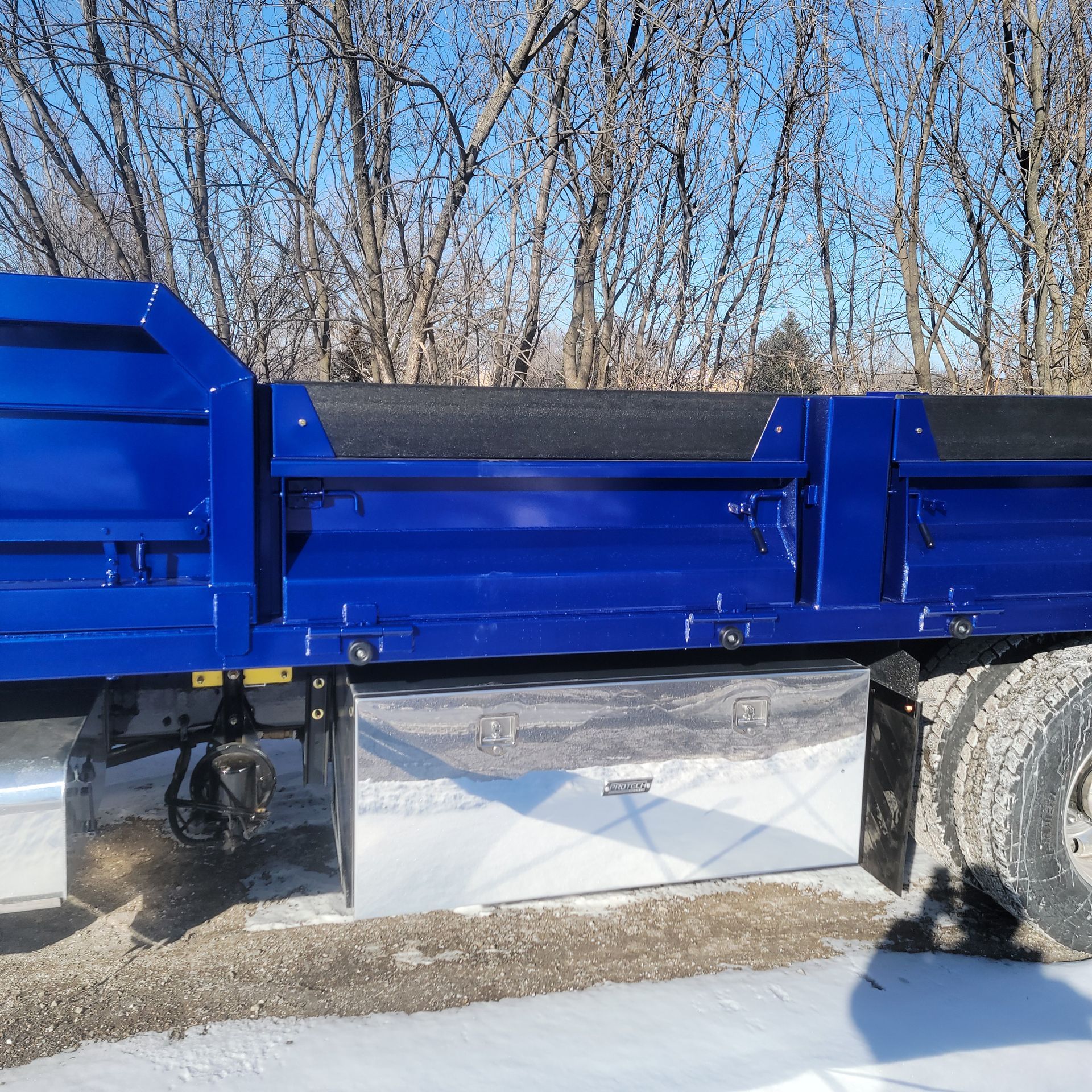 A blue dump truck is parked on the side of the road