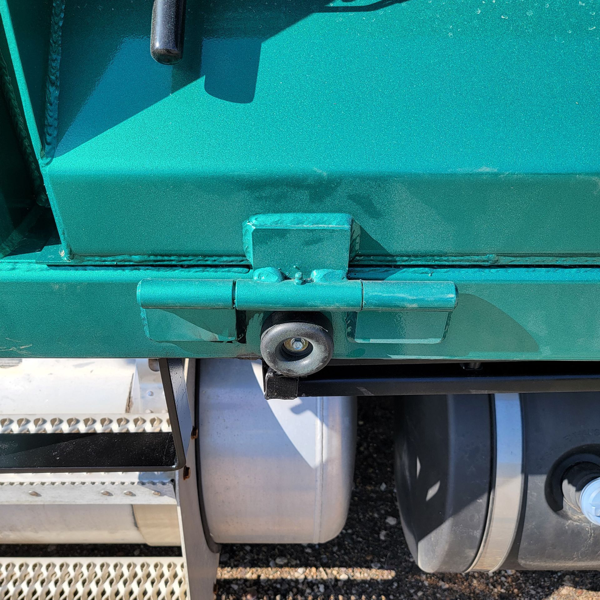 A green truck with a white tank underneath it
