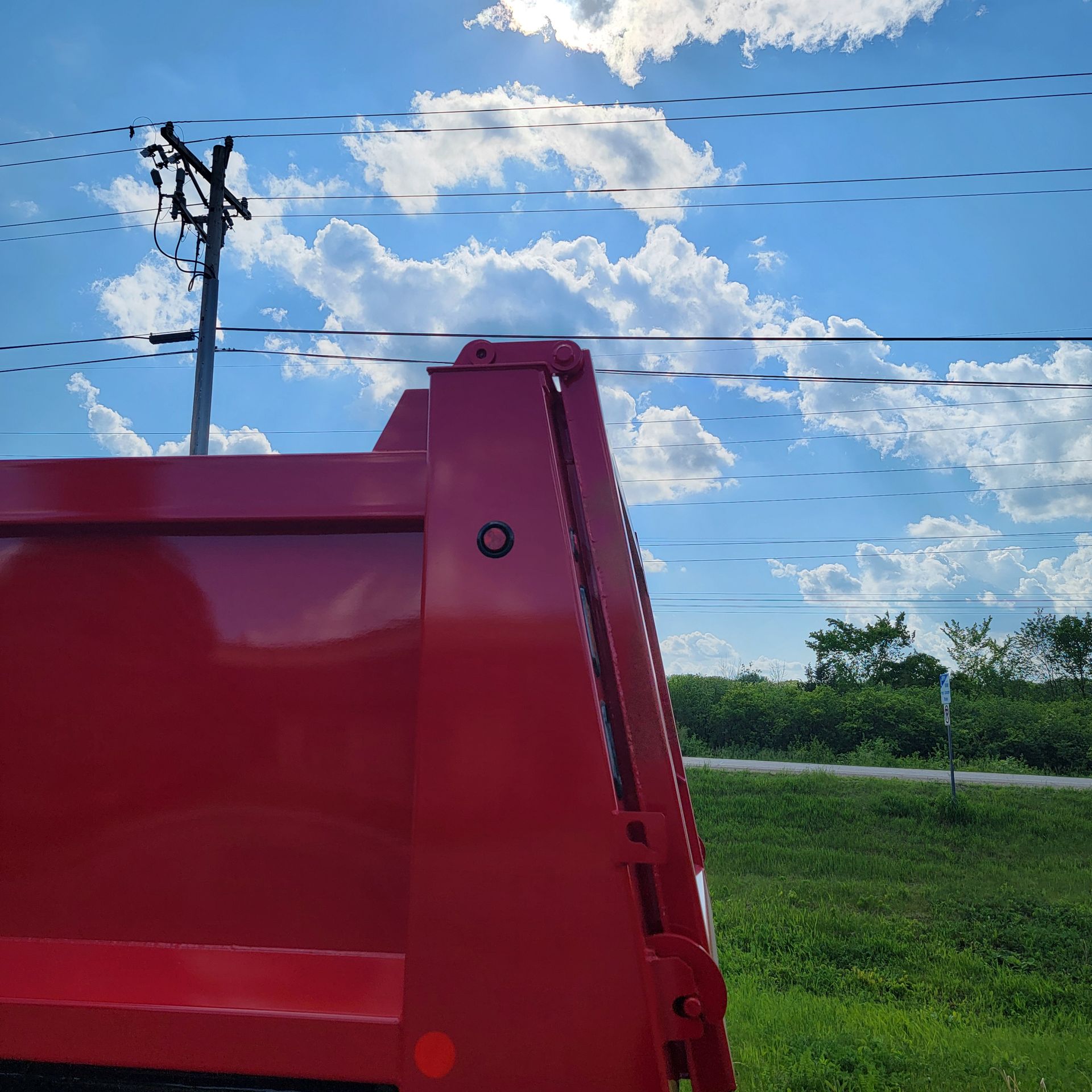 A red dumpster is parked in a grassy field