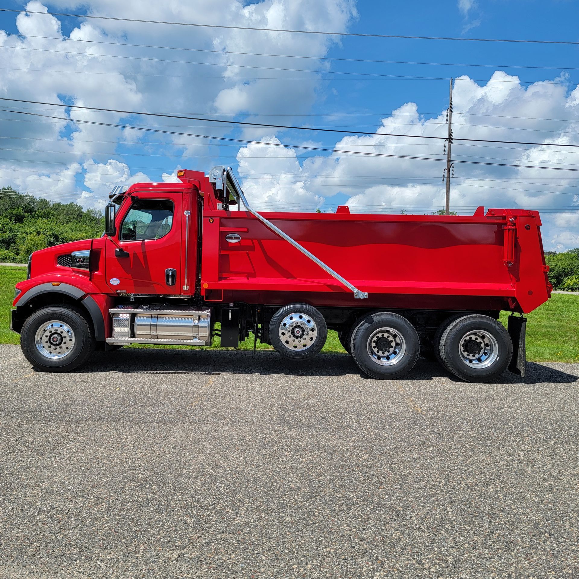 A red dump truck is parked on the side of the road.