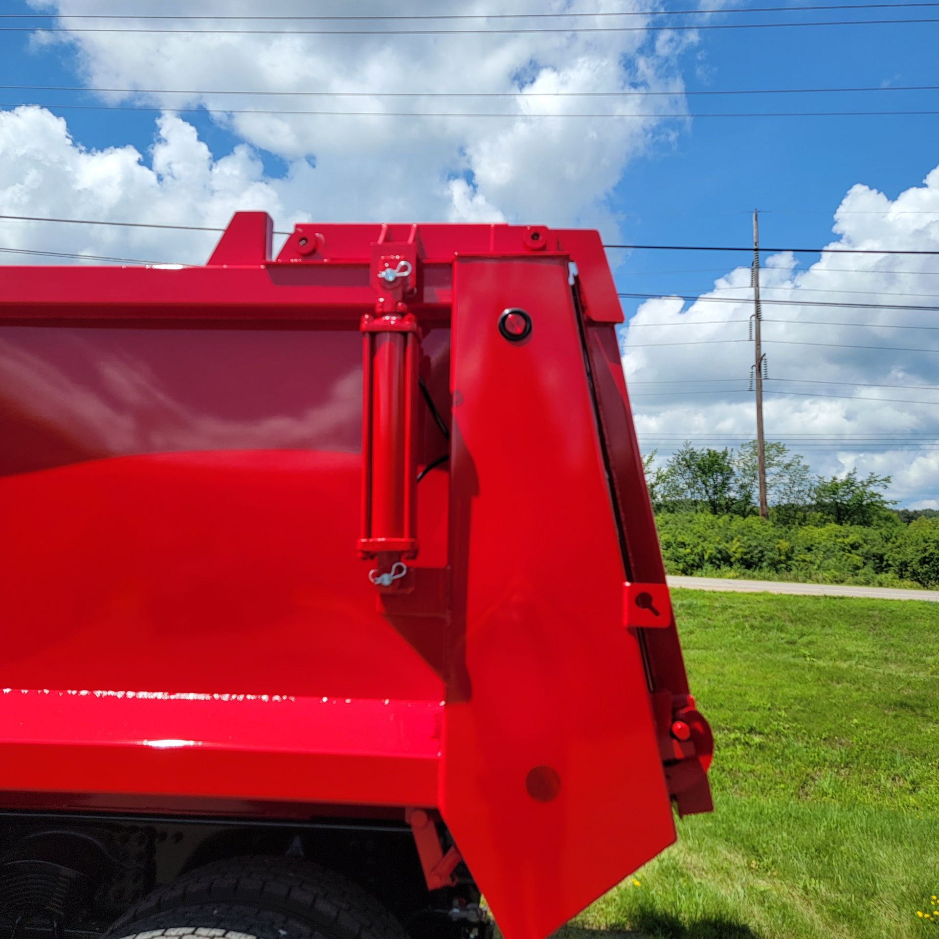 A red dump truck is parked in a grassy field.