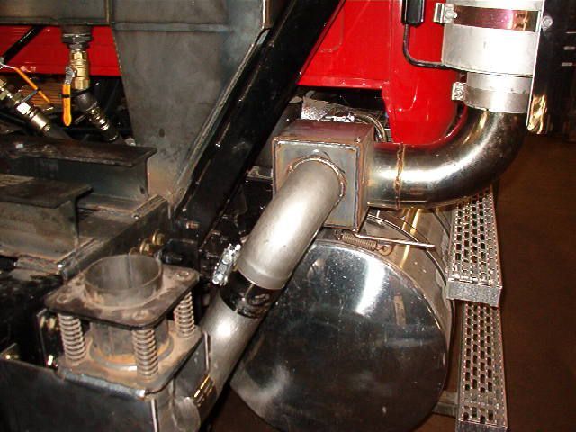 A stainless steel pipe is attached to the side of a red vehicle