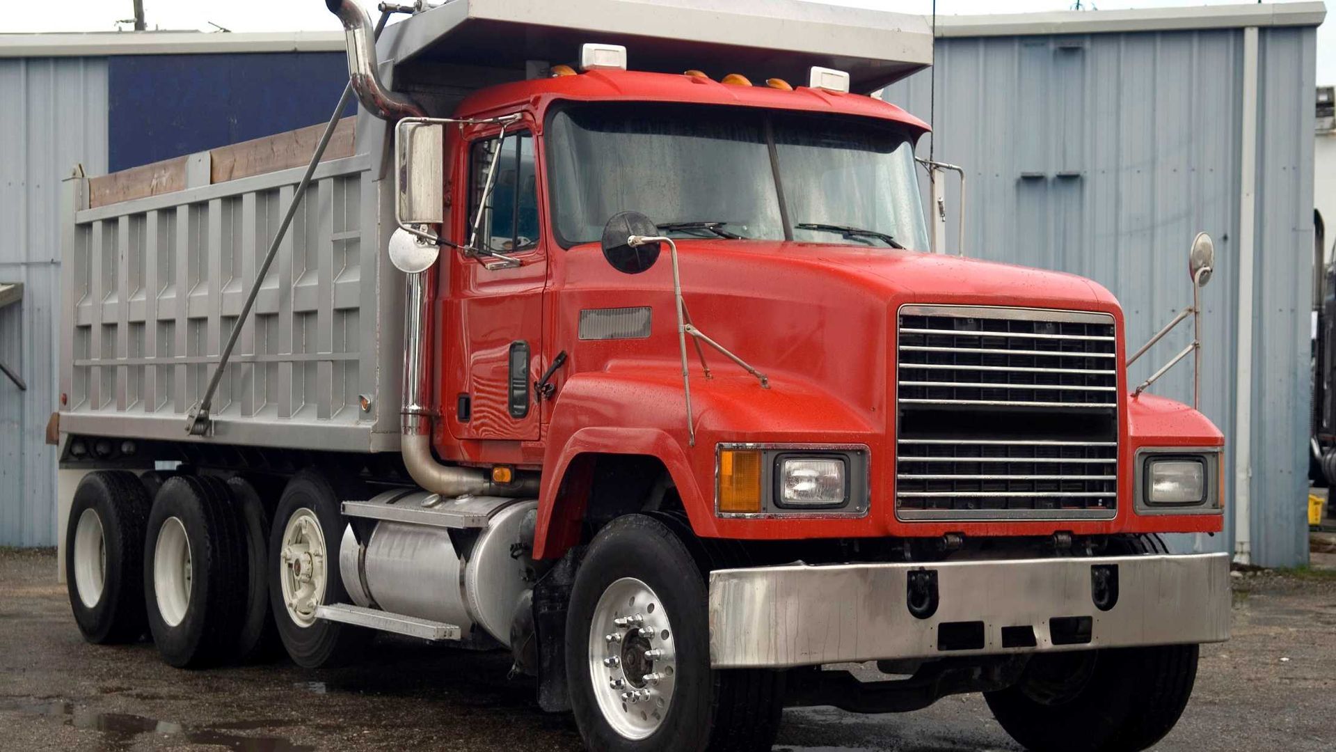 A red dump truck is parked in front of a building
