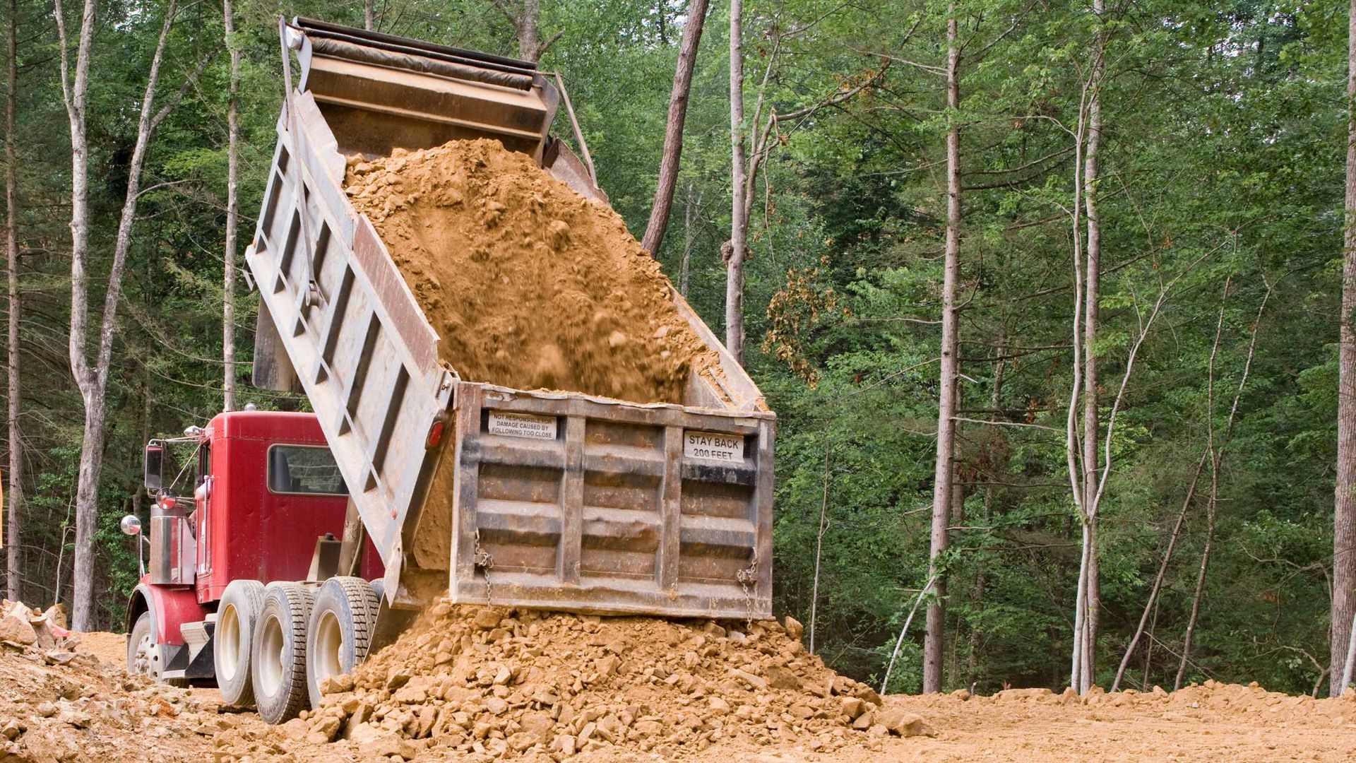 A dump truck is dumping dirt on a construction site.