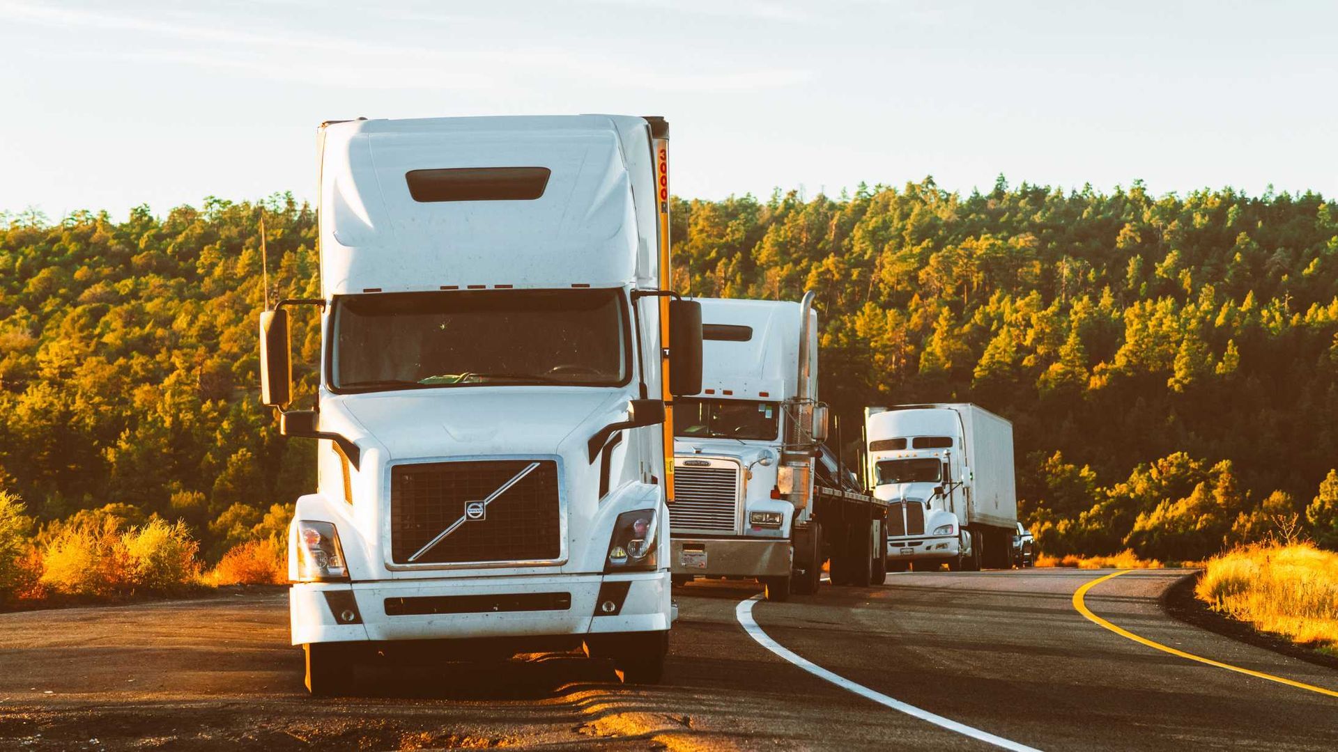 A group of semi trucks are driving down a road.