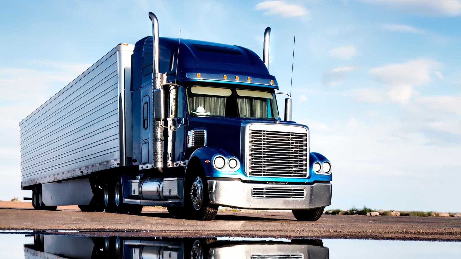 A blue semi truck is parked on the side of the road.