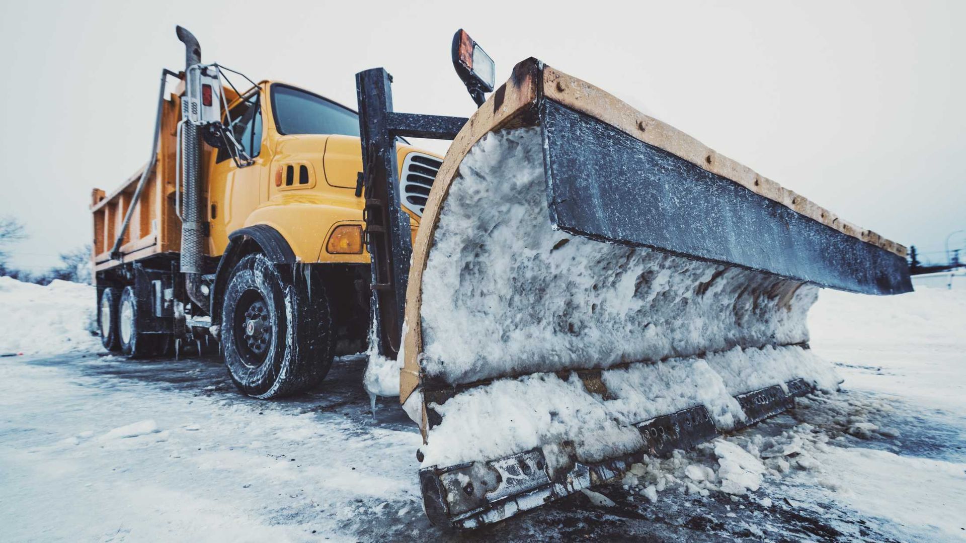 A yellow dump truck with a snow plow attached to it.