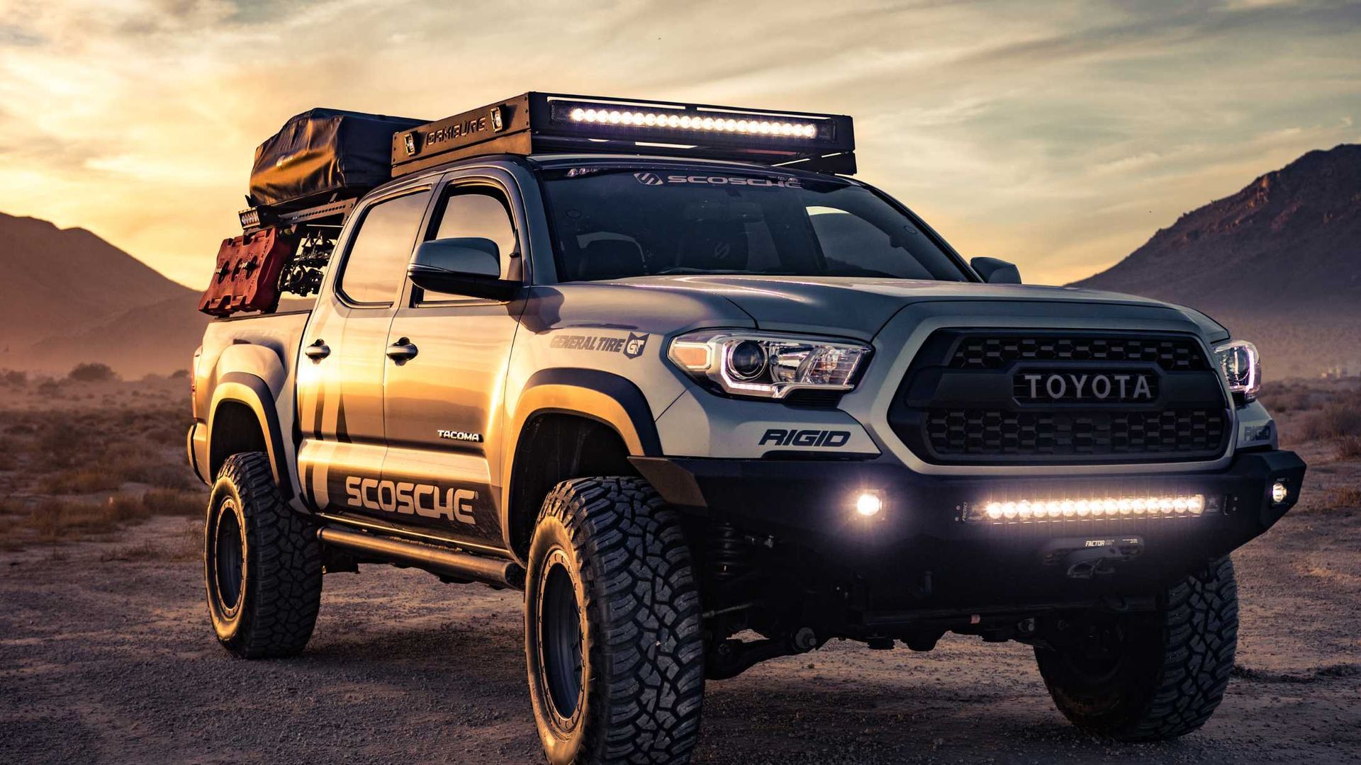 A toyota tacoma truck with a roof rack is parked in the desert.