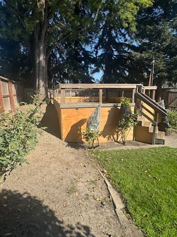 Beige barn-style building with white patches, air conditioning unit, black roof, under a blue sky.