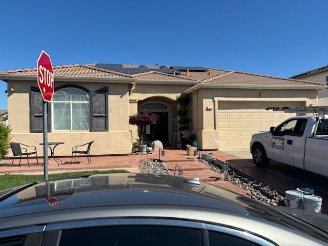 A two-story house with a ladder leaning against it, car in front, cloudy sky.
