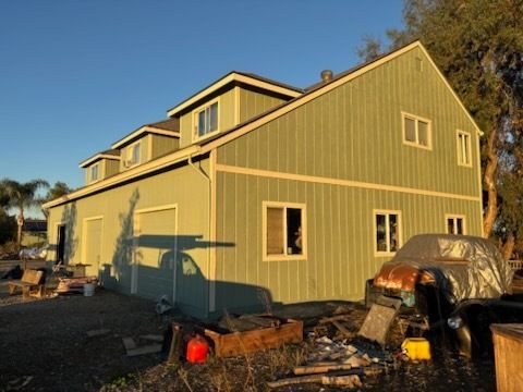 Red wooden tower with black railing and square window, set against a blue sky.