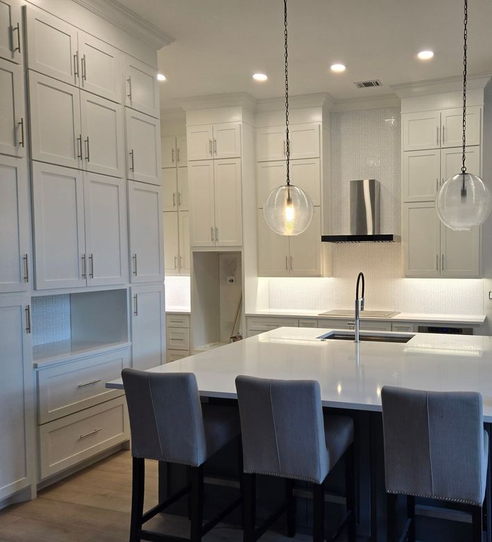 A kitchen with white cabinets and a large island