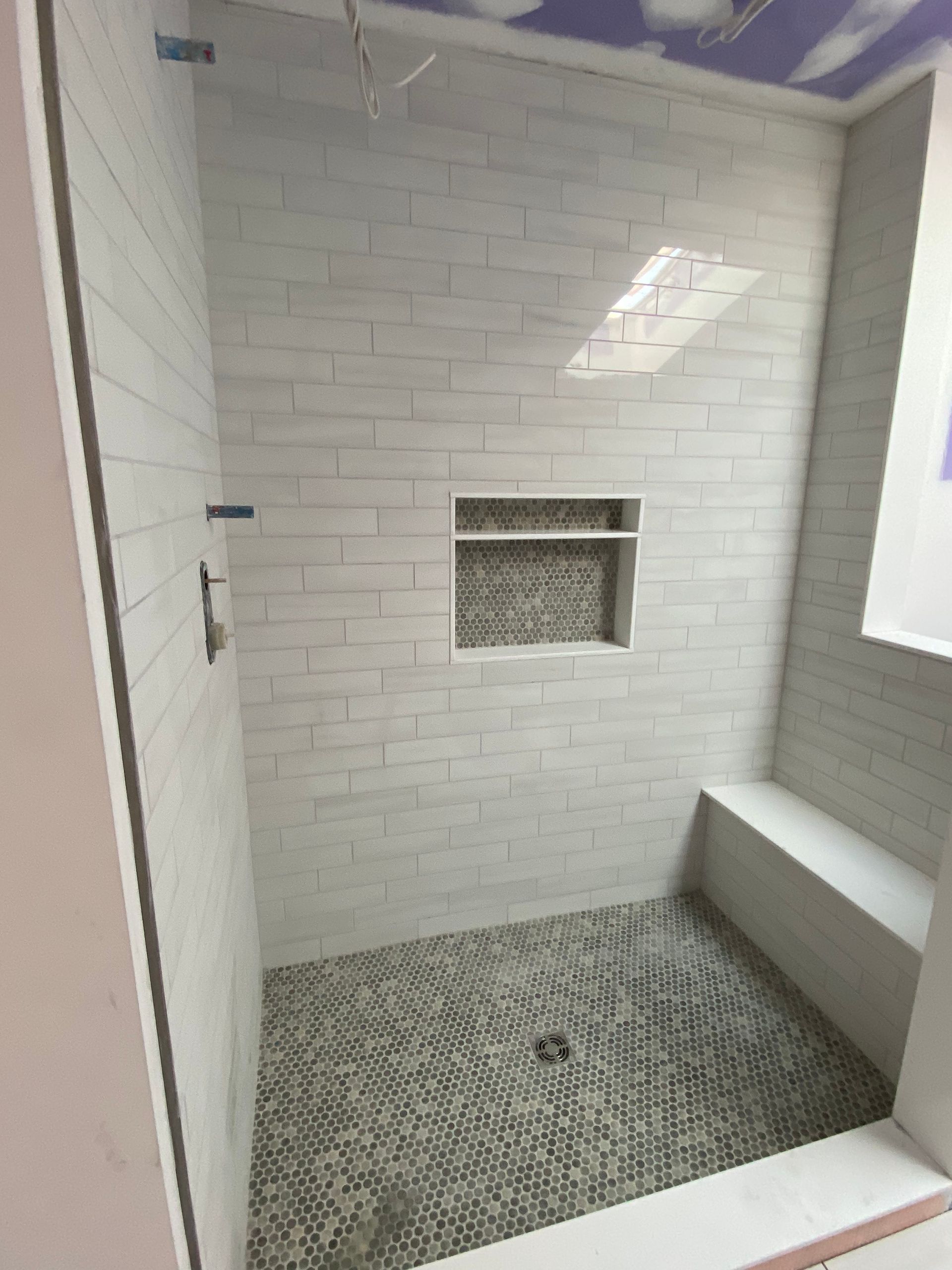 A bathroom with a walk in shower and a bench.