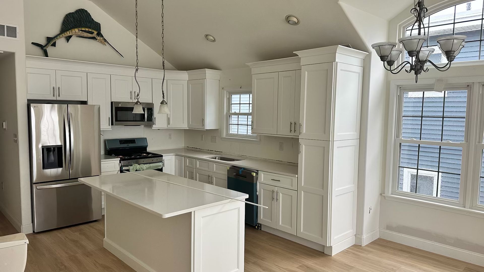A kitchen with white cabinets , stainless steel appliances , and a large island.