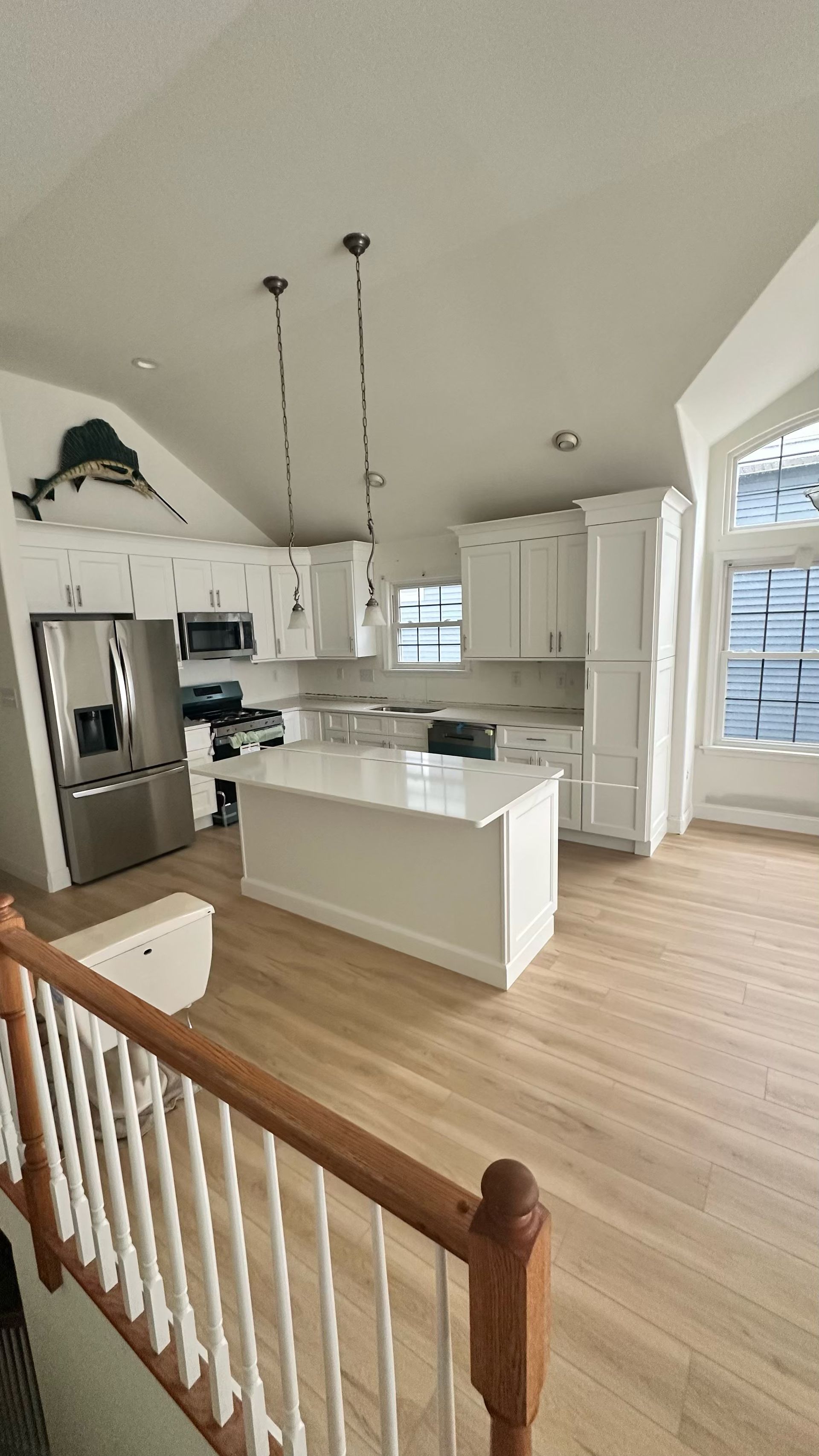 A kitchen with white cabinets , stainless steel appliances , and a large island.