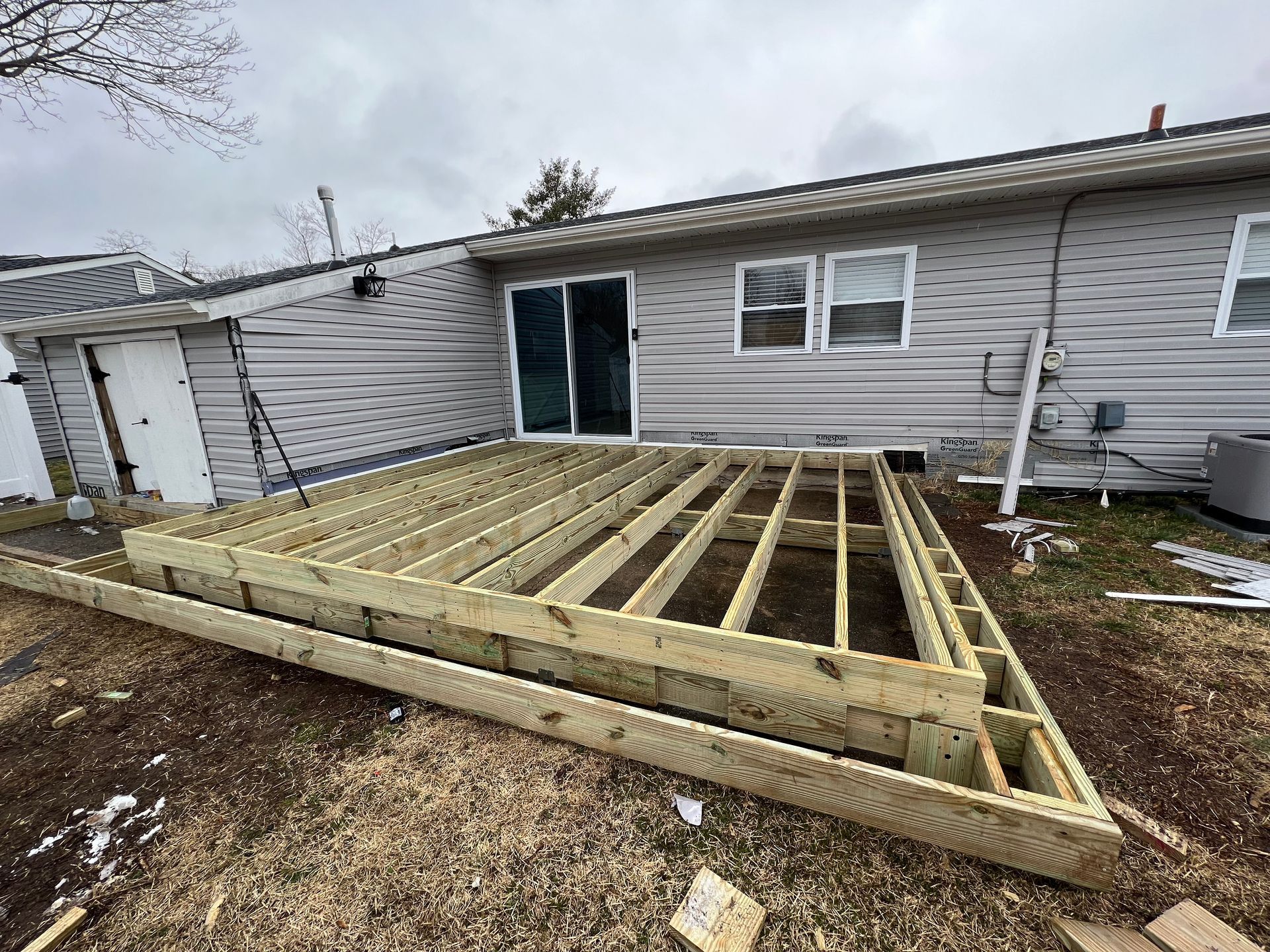 A wooden deck is being built in front of a house.