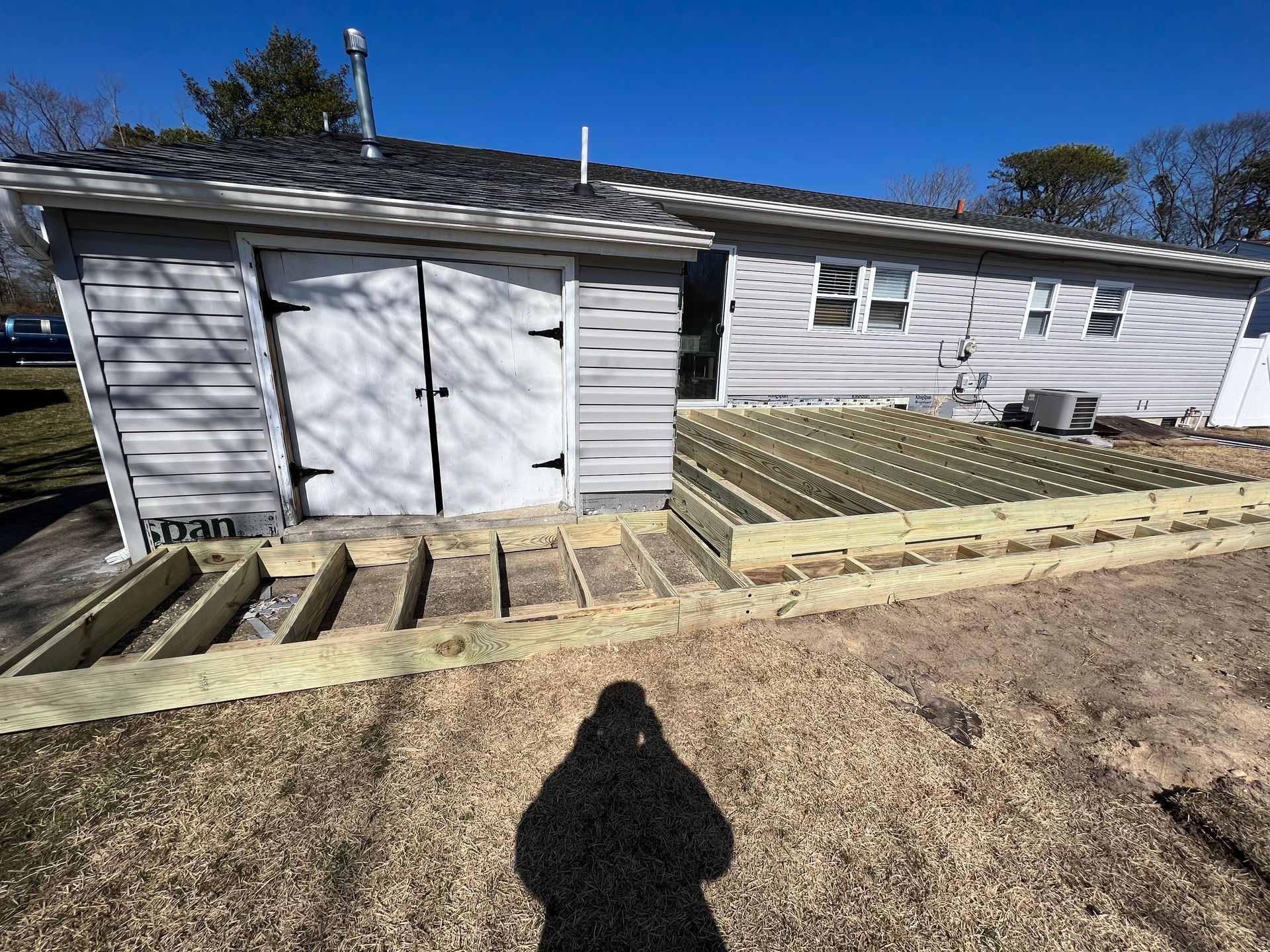 A shadow of a person is cast on the ground in front of a house.