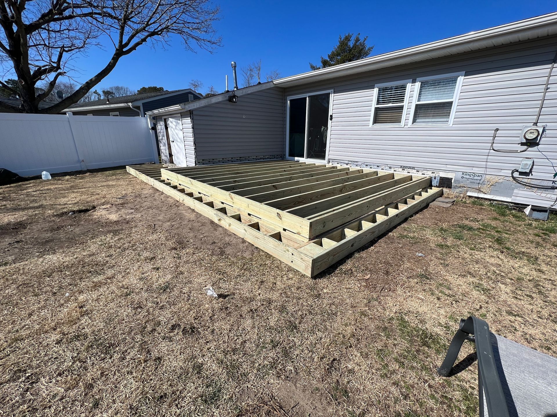 A wooden deck is being built in the backyard of a house.