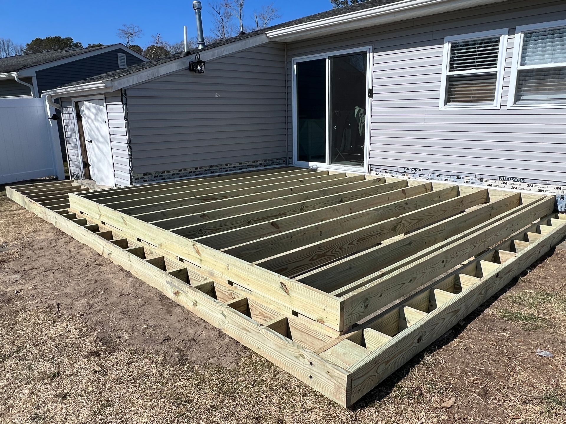 A wooden deck is being built in front of a house.