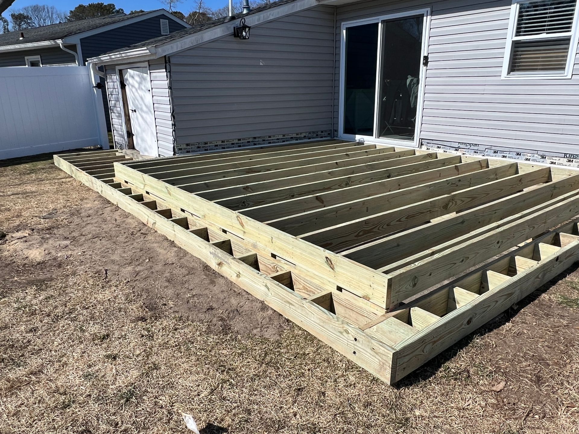 A wooden deck is being built in front of a house.