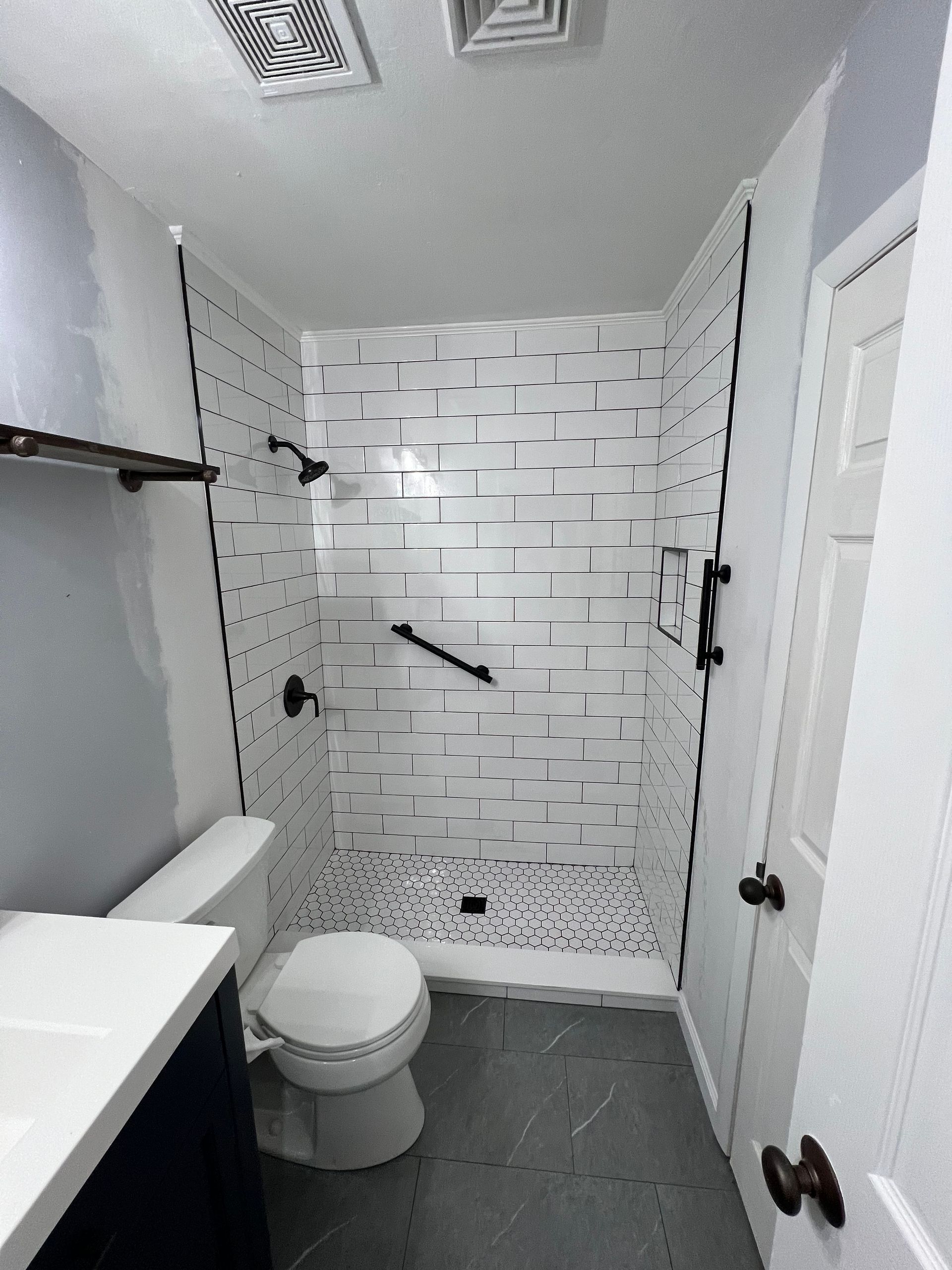 A bathroom with a toilet , sink and shower.