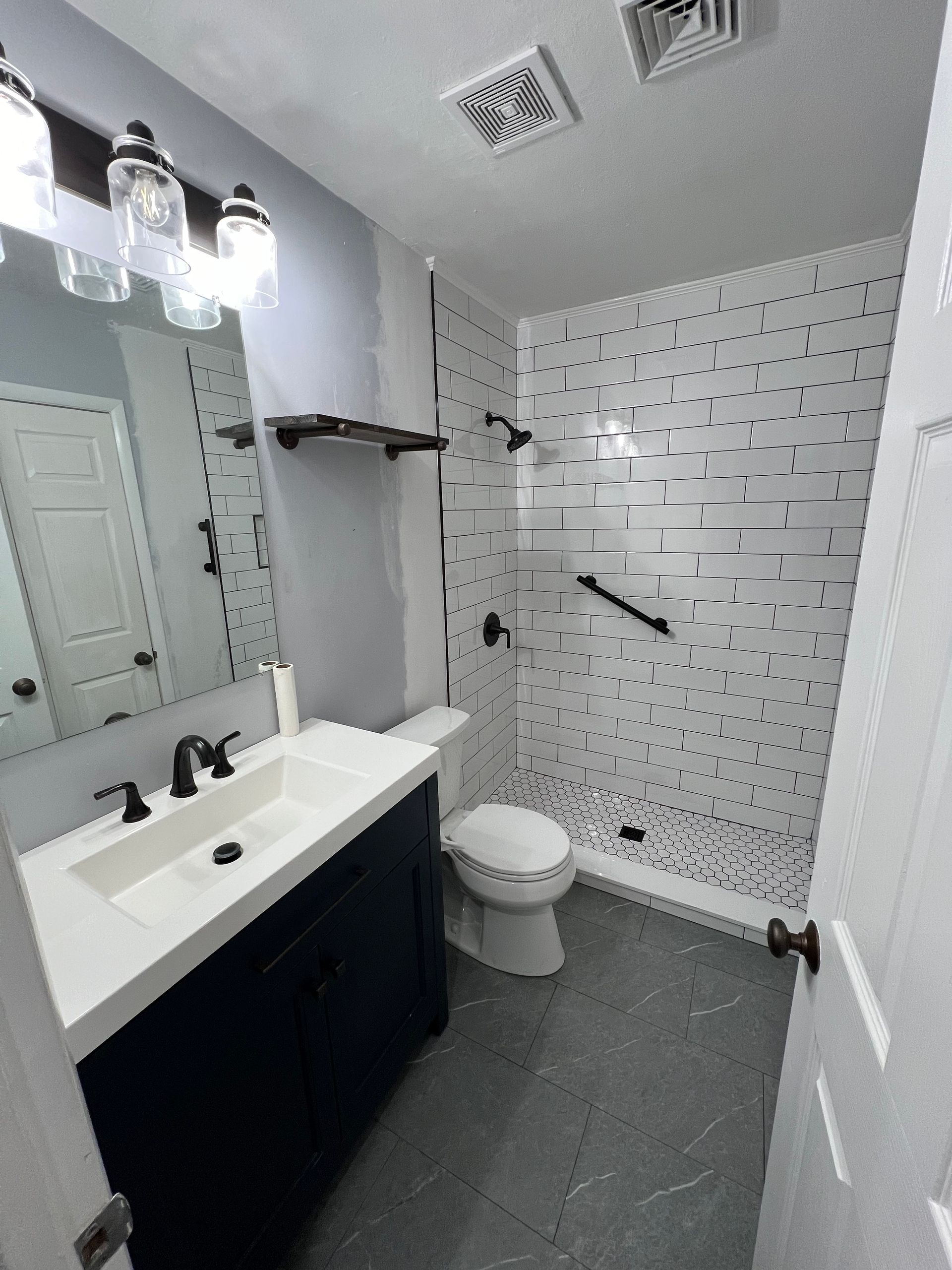 A bathroom with a sink , toilet , shower and mirror.