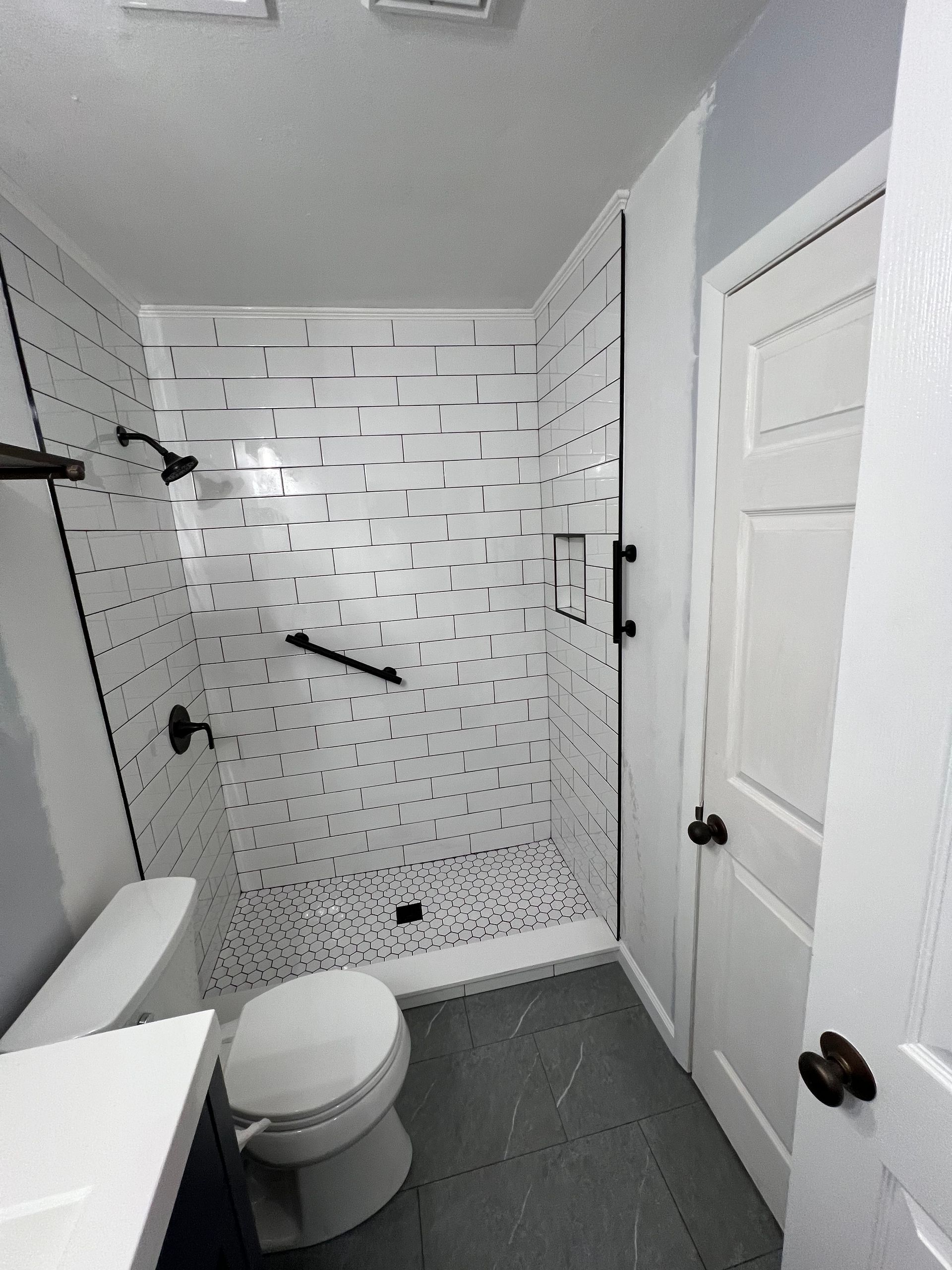 A bathroom with a toilet , sink and shower.