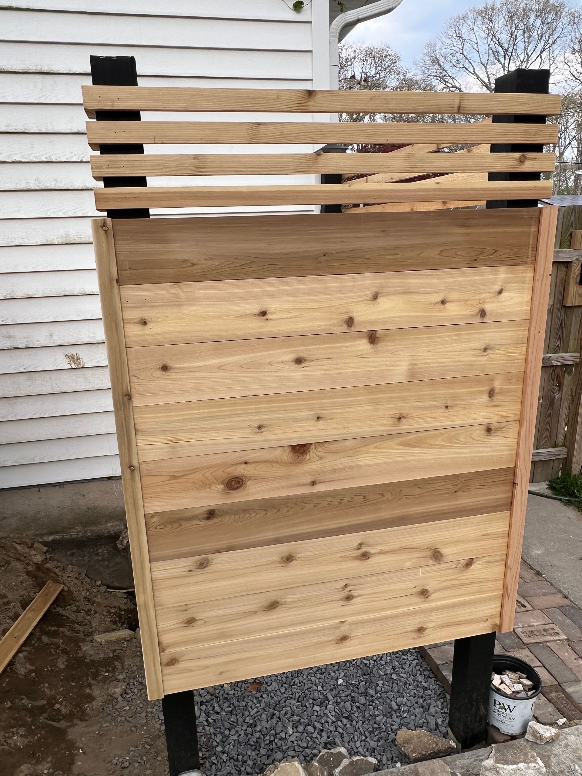 A wooden fence is sitting in front of a white house.