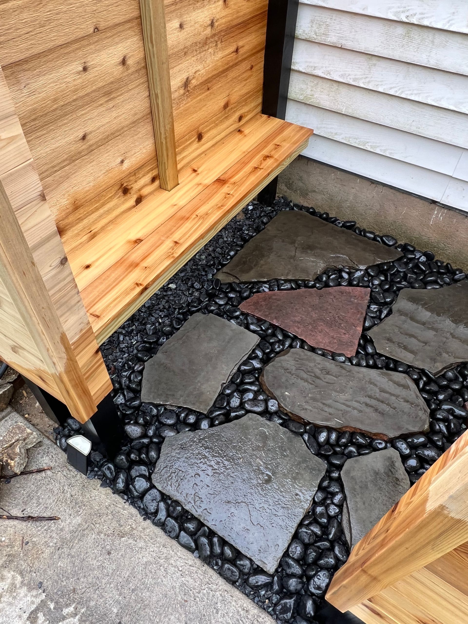 A wooden bench is sitting next to a stone walkway.