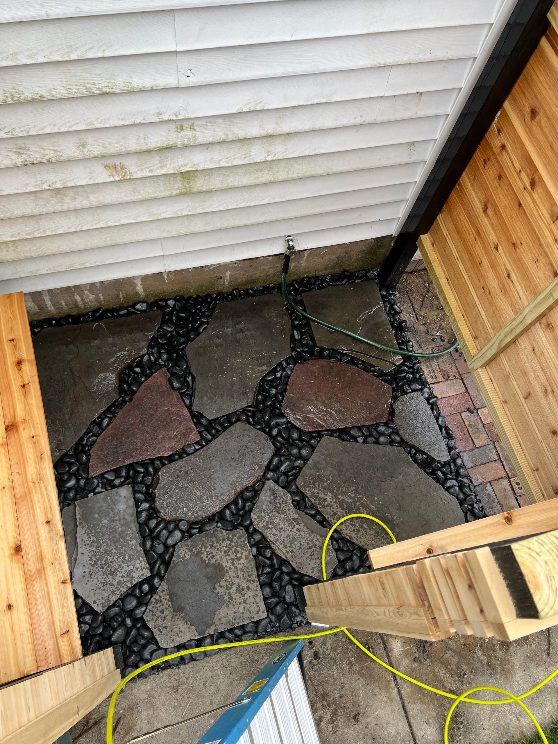 A stone walkway is being built in the backyard of a house.