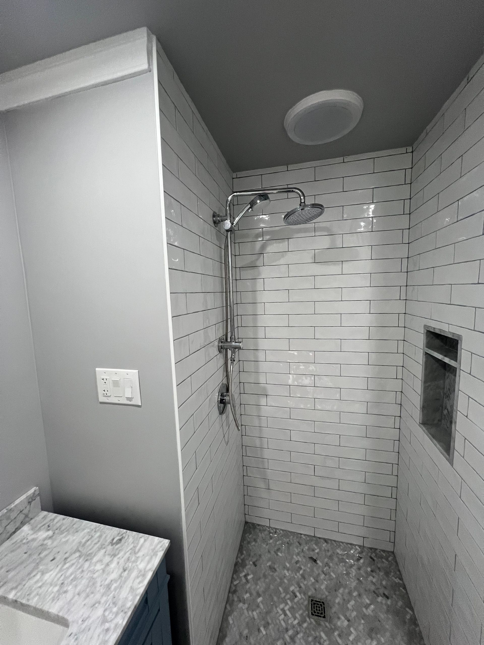 A bathroom with a walk in shower and a sink.