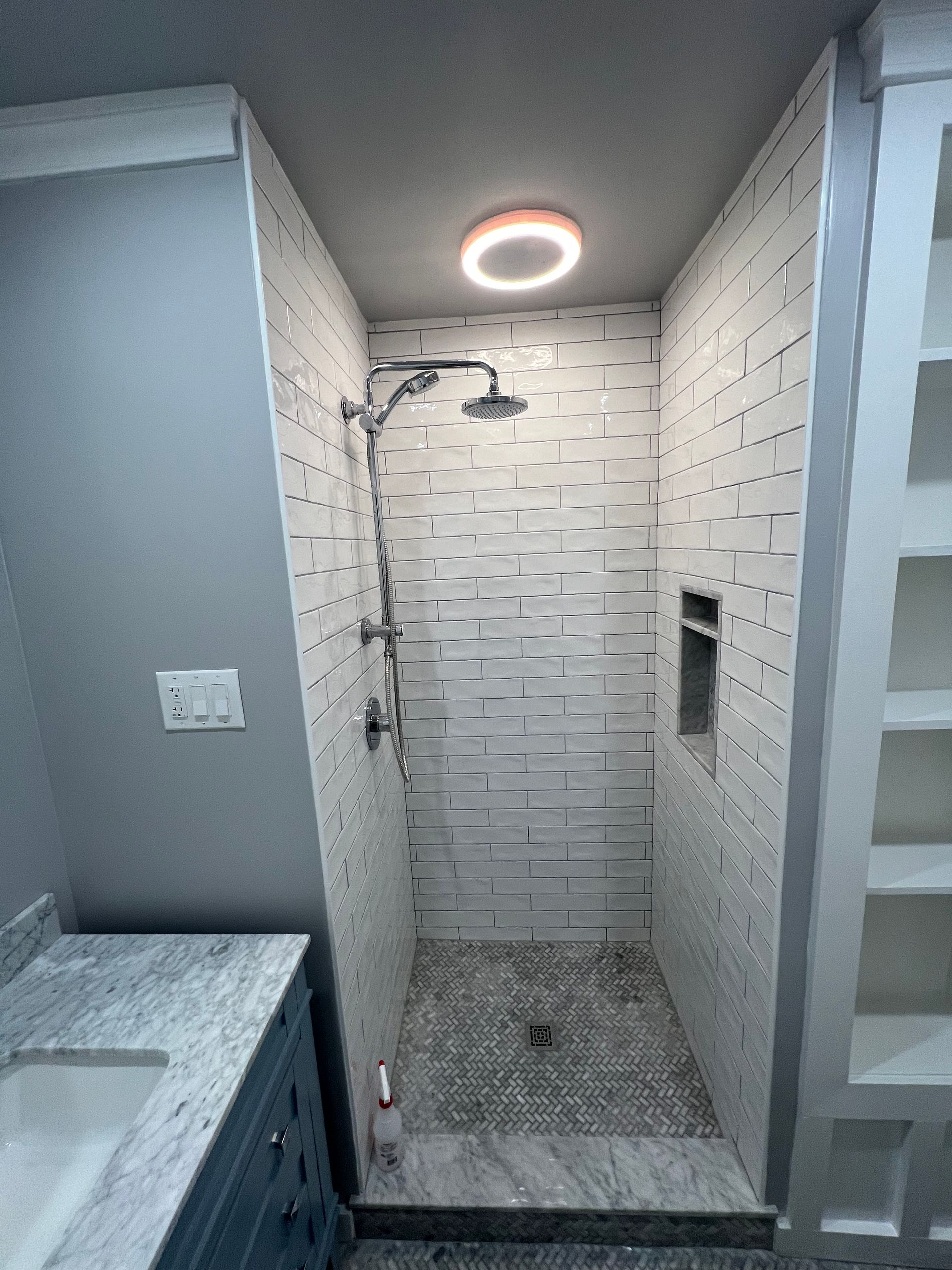 A bathroom with a walk in shower and a sink.
