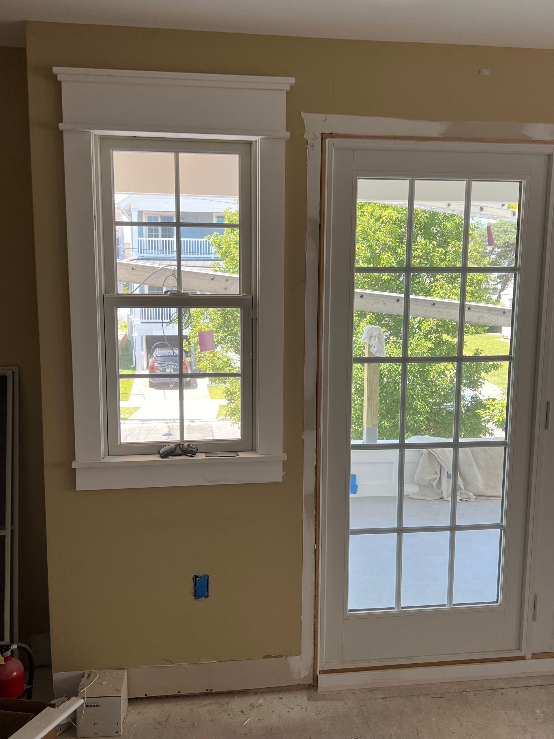 A living room with two windows and a sliding glass door
