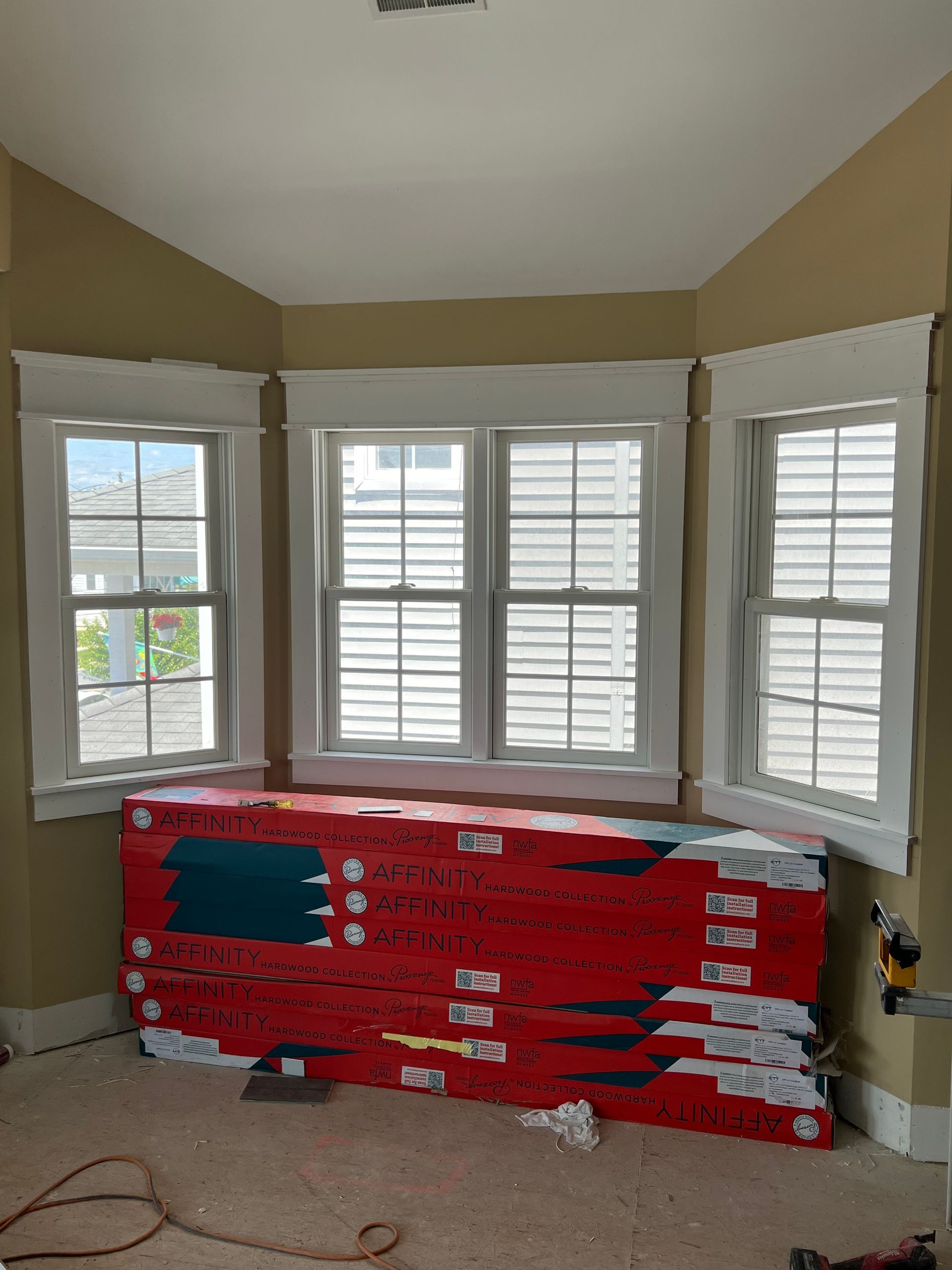 A room with a lot of windows and a stack of boxes on the floor.