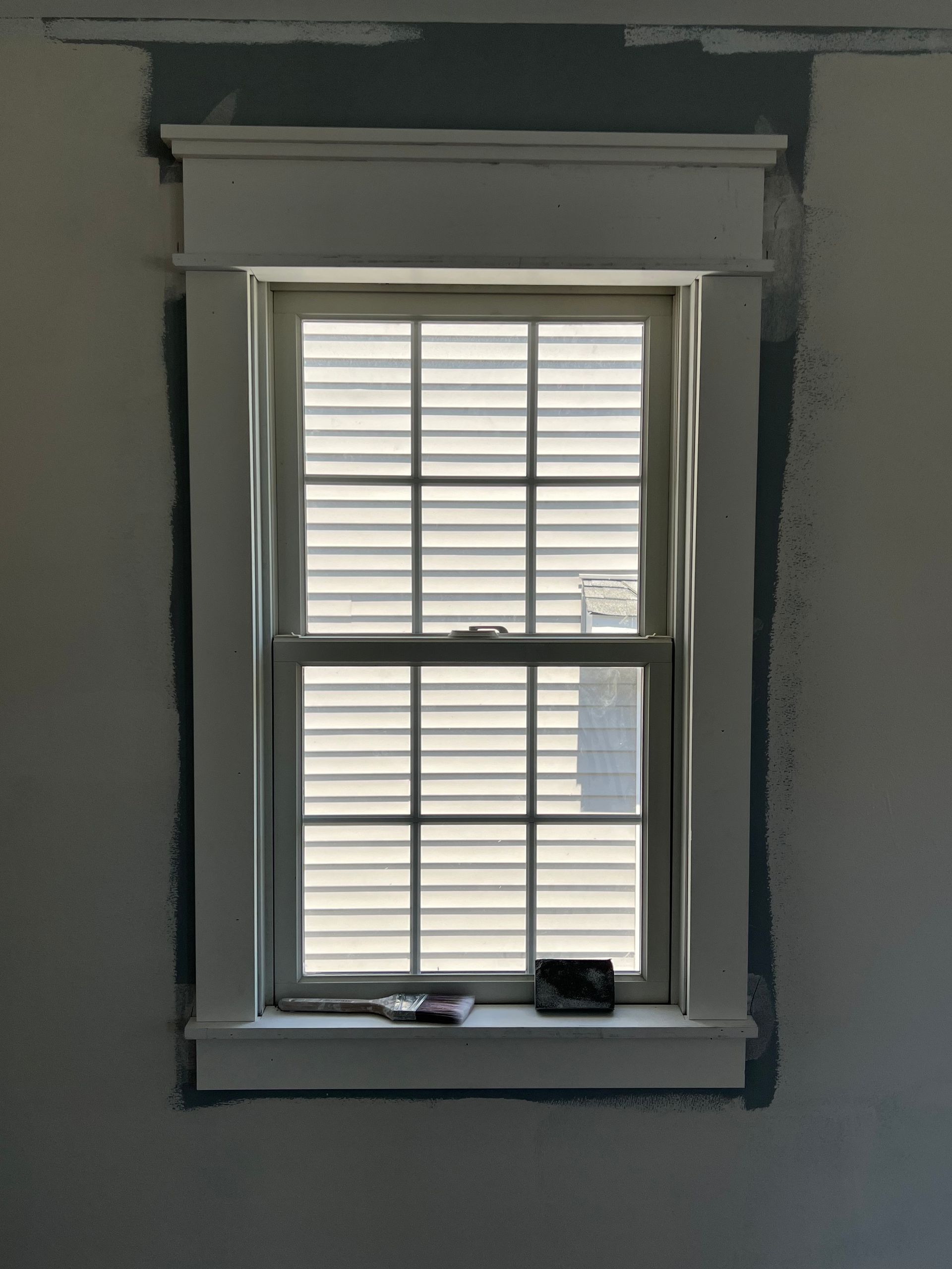 A window with shutters is sitting on a window sill in a room.