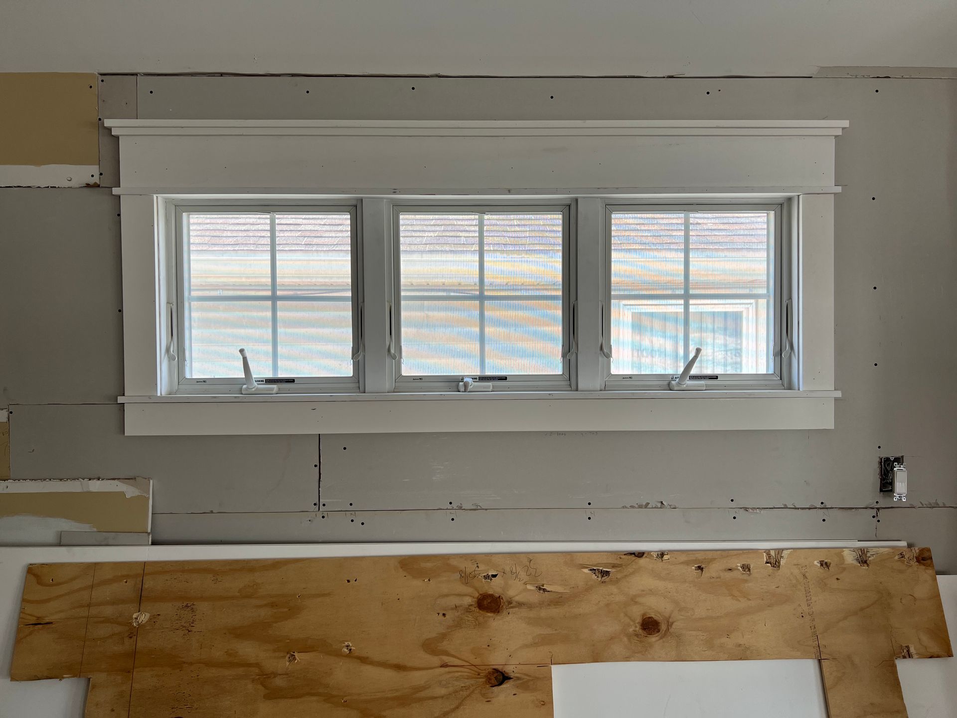 A room with three windows and a wooden headboard.