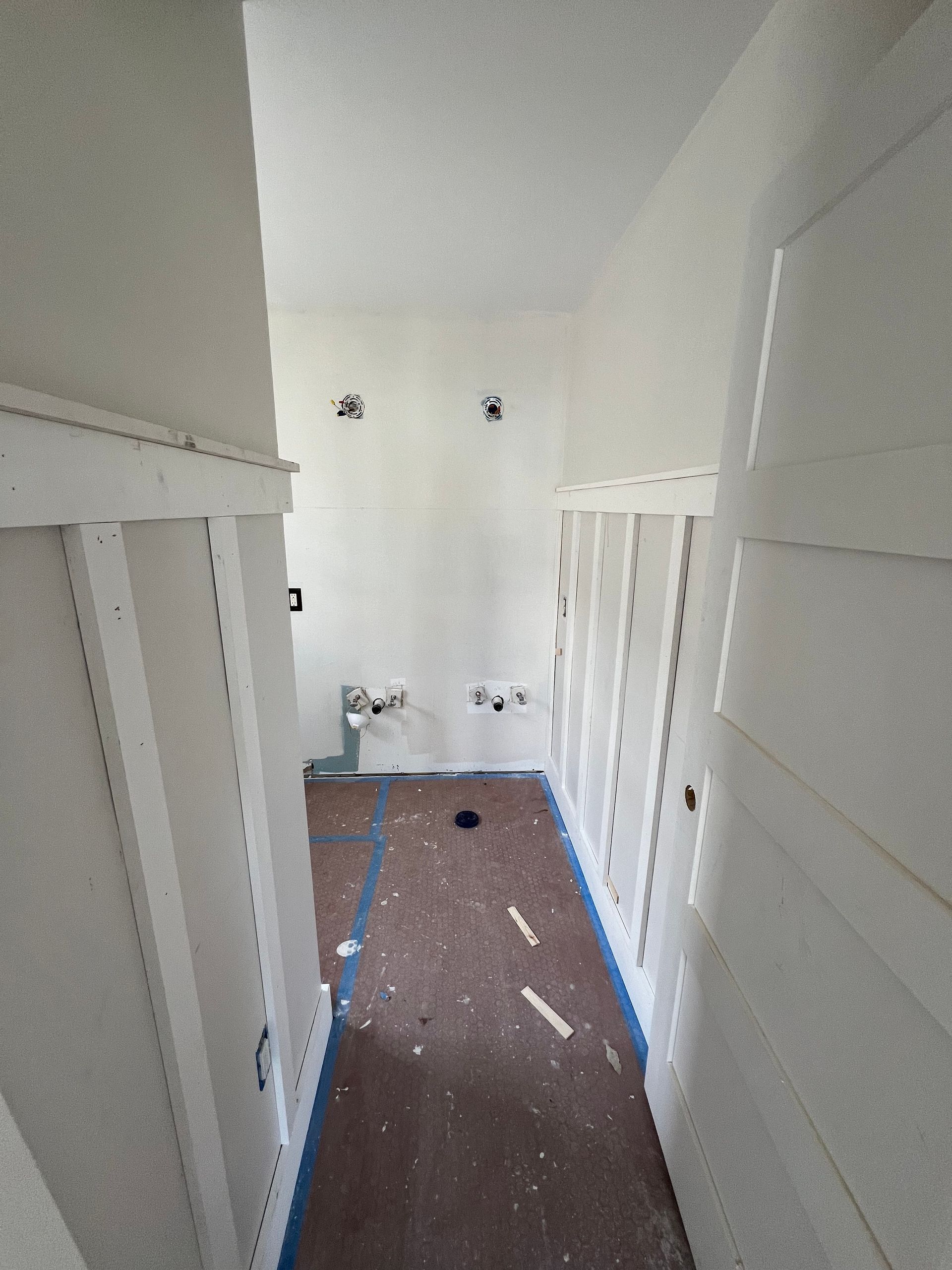 A hallway with white walls and blue tape on the floor