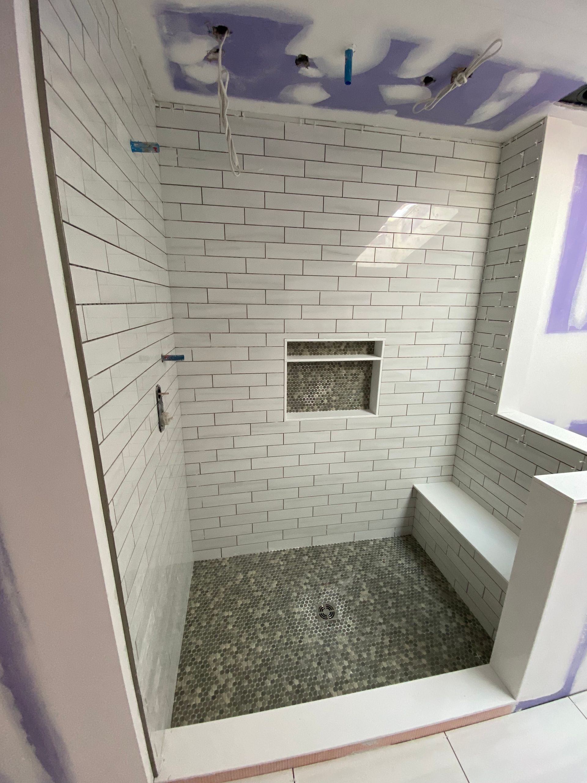 A shower with a brick wall and a bench in it