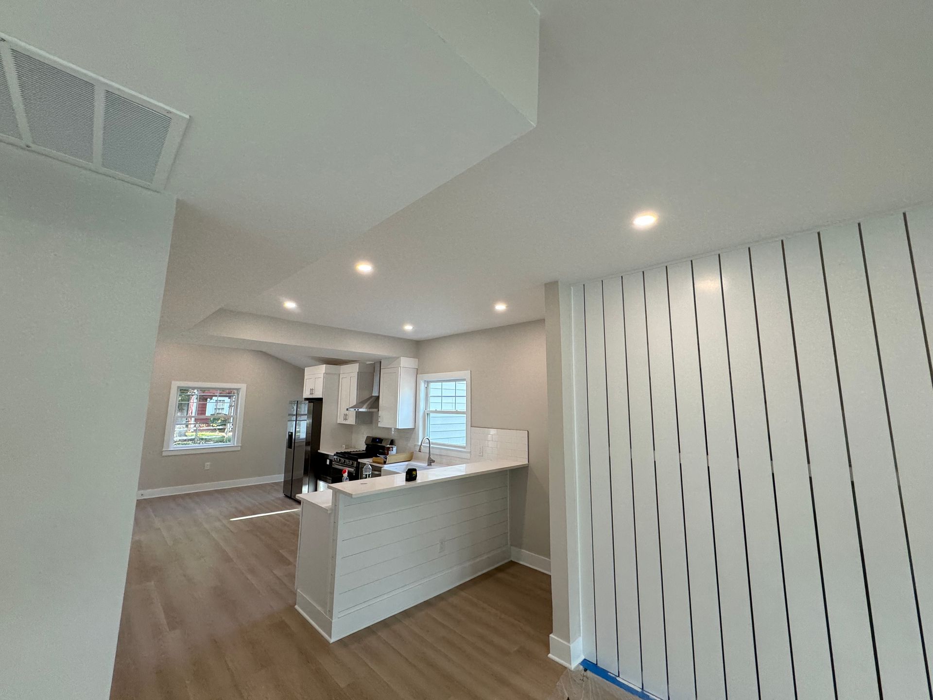 A kitchen with a bar and a refrigerator in a house under construction.