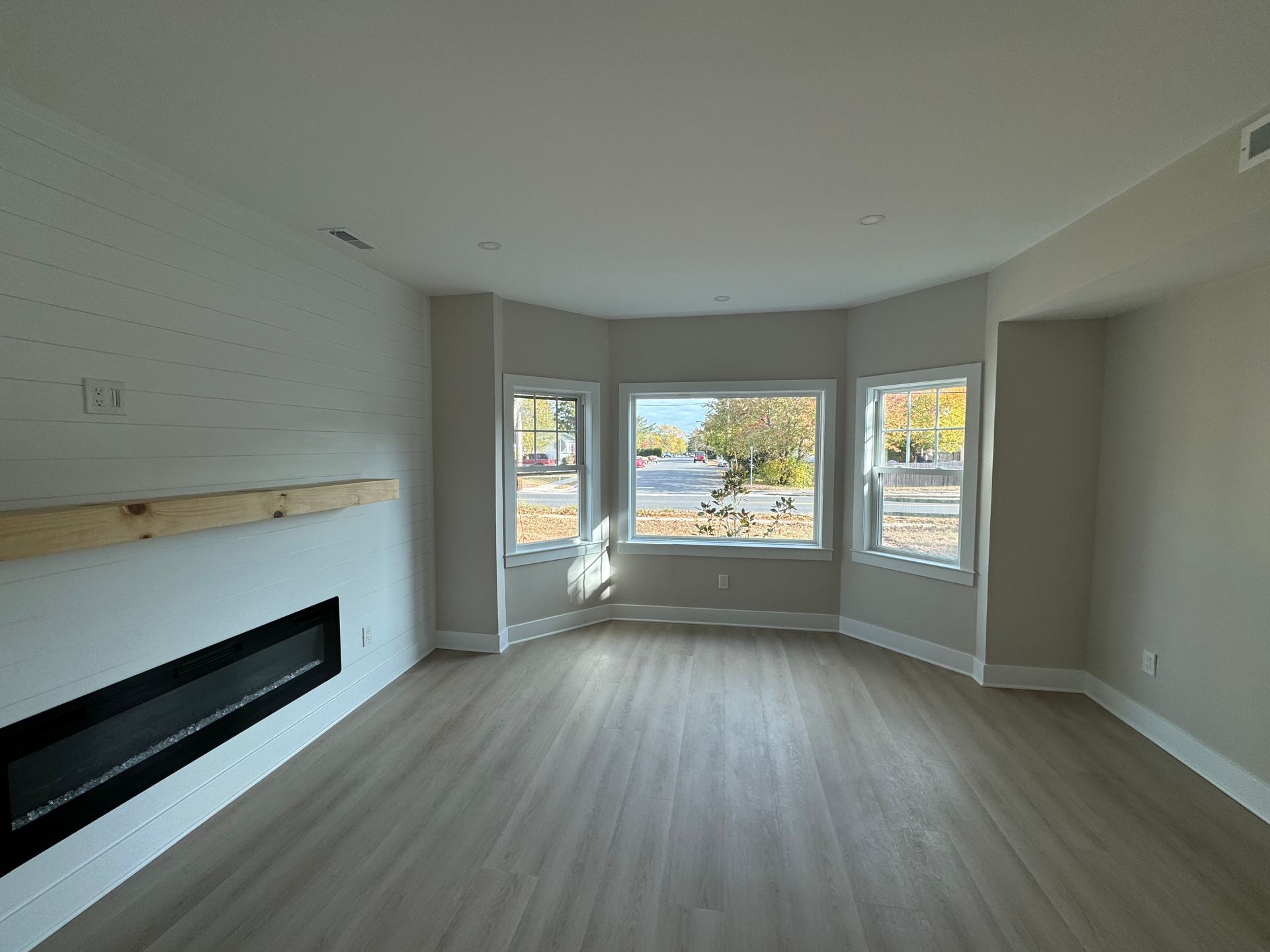 An empty living room with a fireplace and lots of windows.