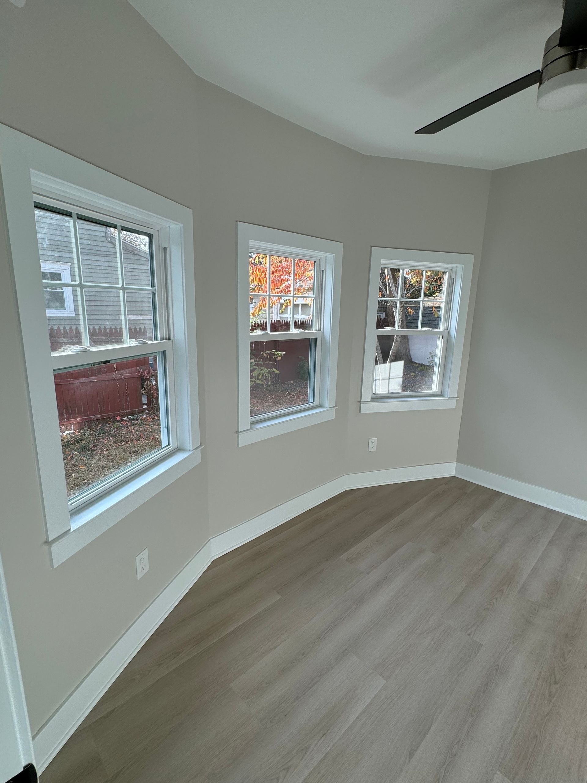 A room with a lot of windows and a ceiling fan.